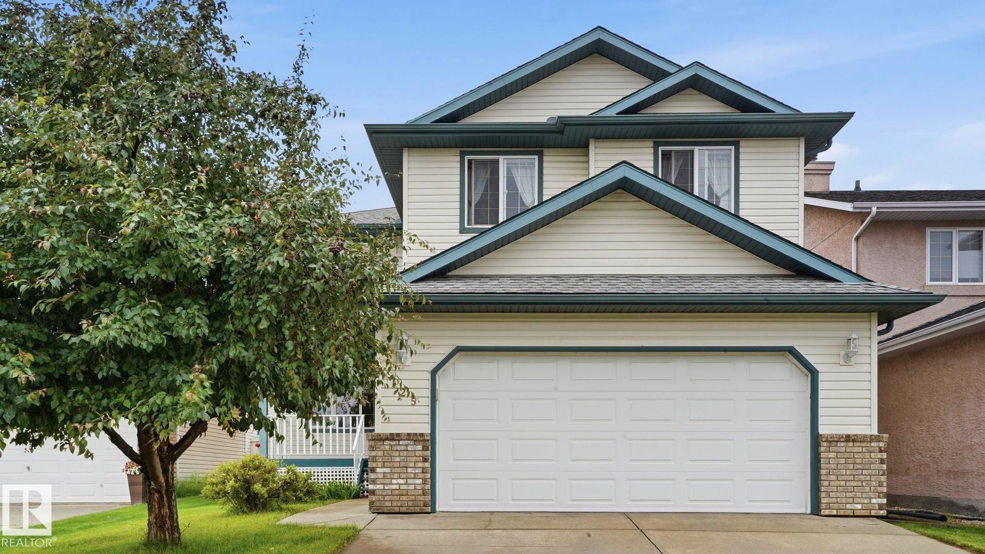 Two-story residence featuring light-colored siding with dark trim accents, an attached garage, and brick detailing on the facade - 125 Dechene Road Nw, Edmonton, AB - Outdoor