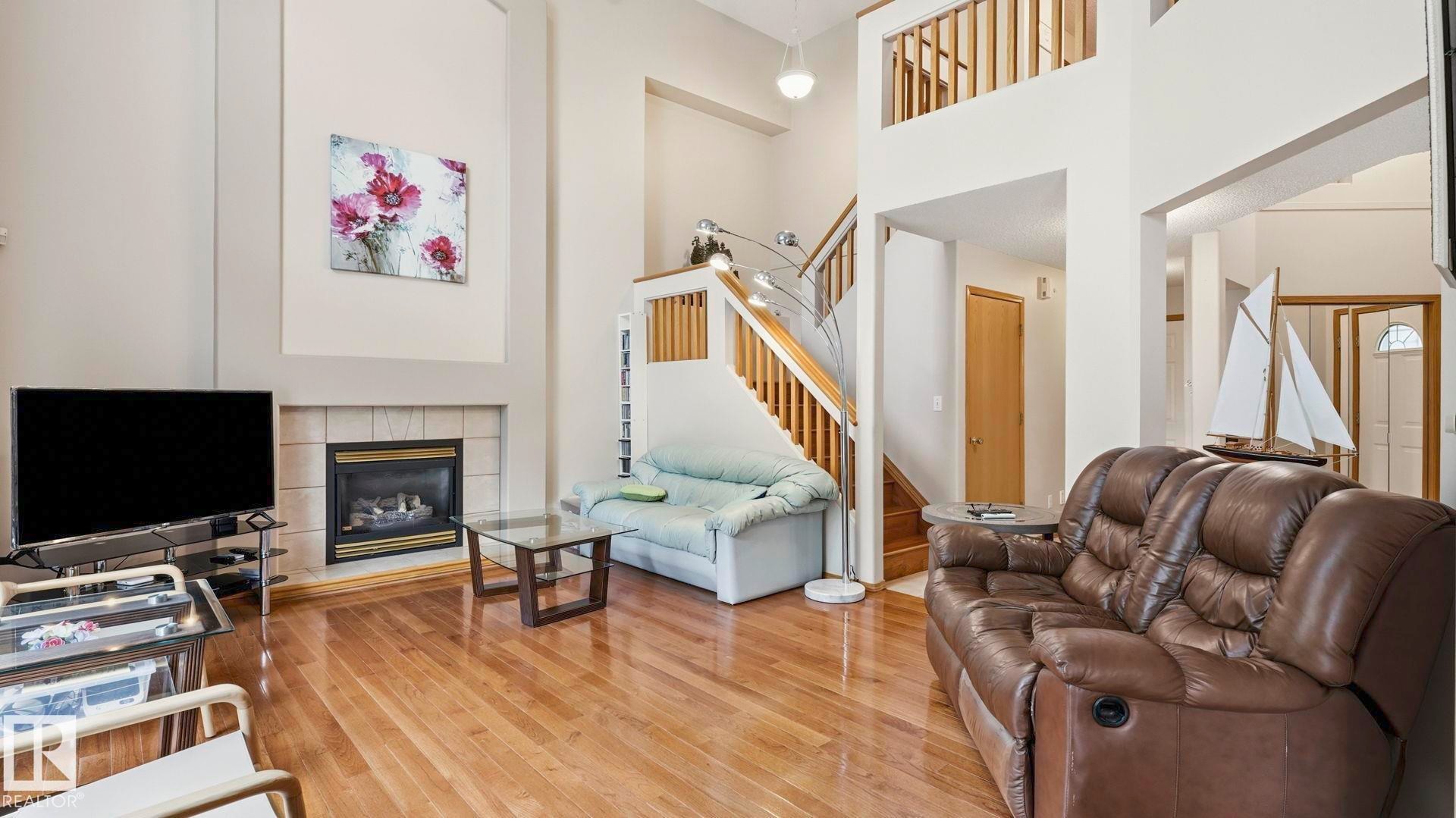 Vaulted ceilings highlight the living area, featuring wood-finish flooring and a tiled fireplace - 125 Dechene Road Nw, Edmonton, AB - Indoor Photo Showing Other Room With Fireplace