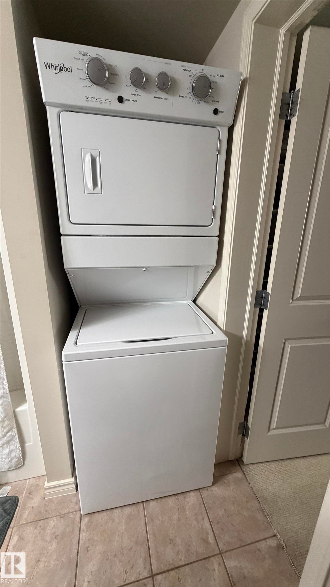 White stackable washer and dryer unit with top controls - #2401 10180 104 St Nw, Edmonton, AB - Indoor Photo Showing Laundry Room