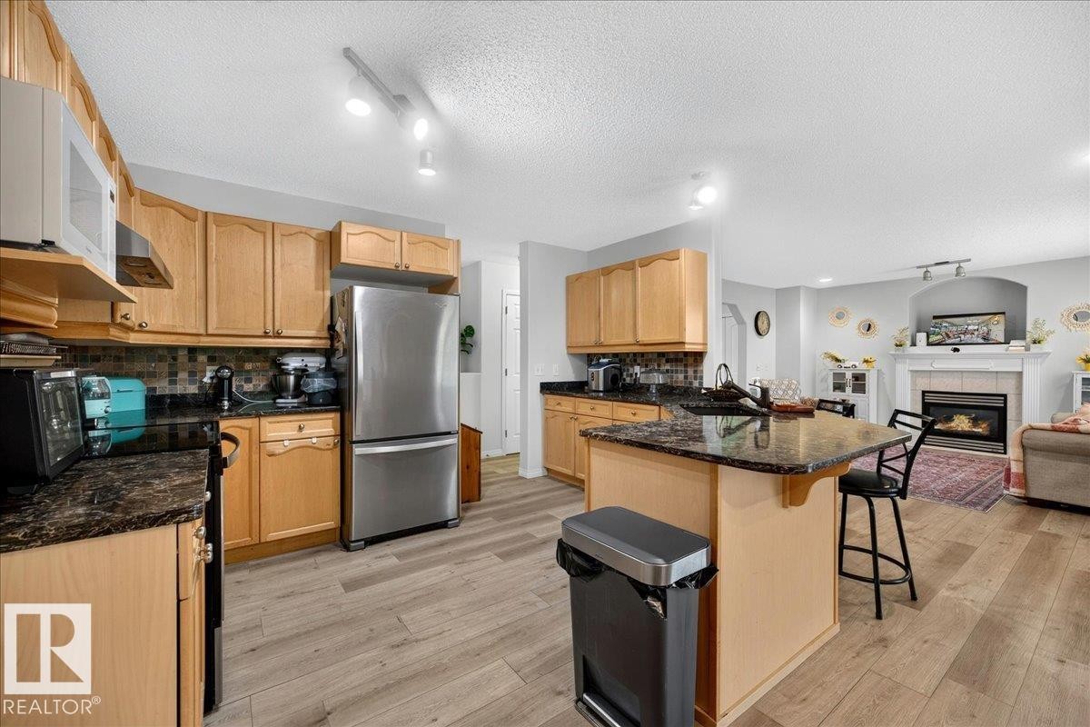 Kitchen featuring wood-finish flooring and light wood cabinetry - 6 Norfolk Close, St. Albert, AB - Indoor Photo Showing Kitchen With Fireplace
