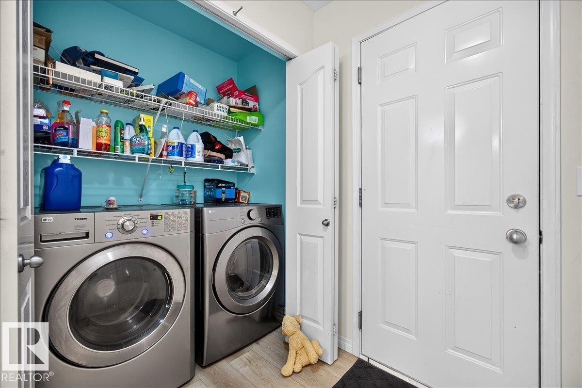 Laundry area featuring a side-by-side washer and dryer, wire shelving, and wood-finish flooring - 6 Norfolk Close, St. Albert, AB - Indoor Photo Showing Laundry Room