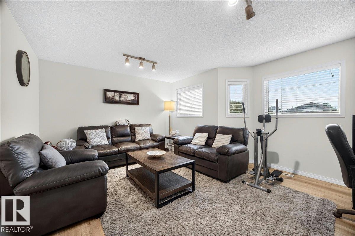 Living area featuring neutral wall tones, wood-finish flooring, and multiple windows with blinds - 6 Norfolk Close, St. Albert, AB - Indoor Photo Showing Living Room