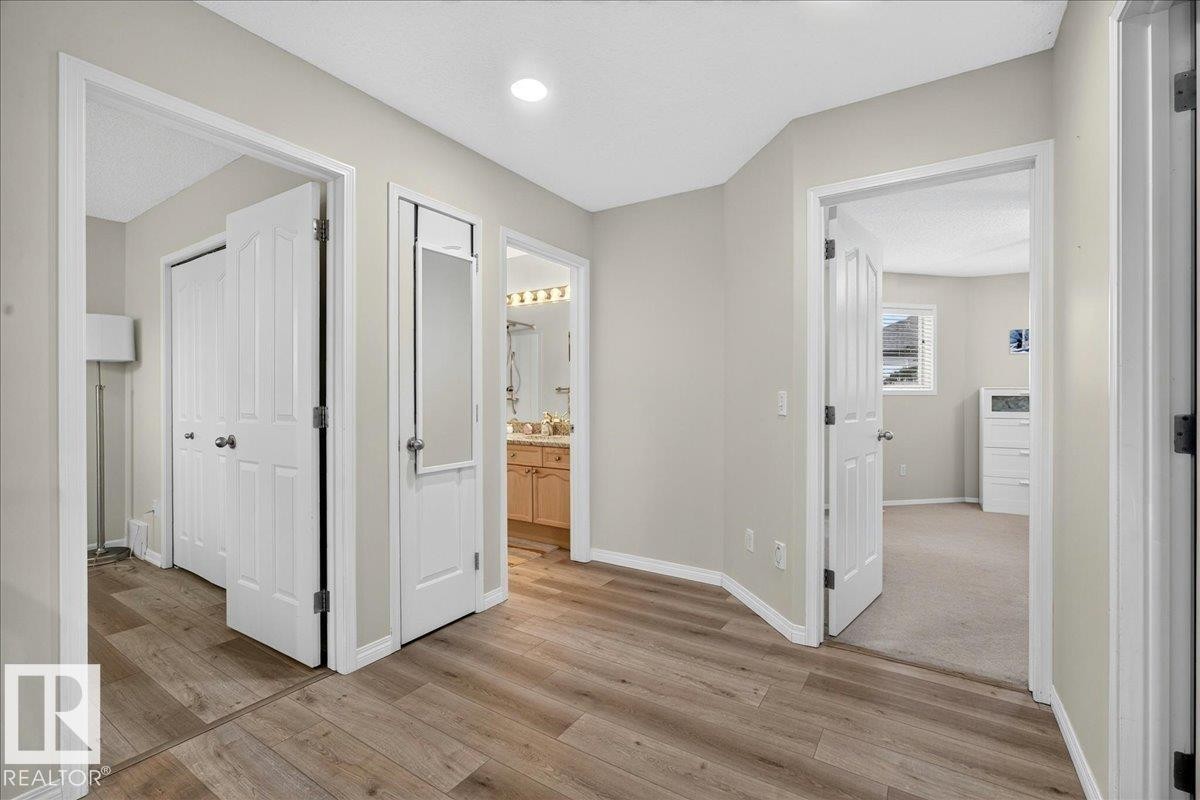 Hallway featuring wood-finish flooring, light neutral wall paint, recessed lighting, and white paneled doors - 6 Norfolk Close, St. Albert, AB - Indoor Photo Showing Other Room