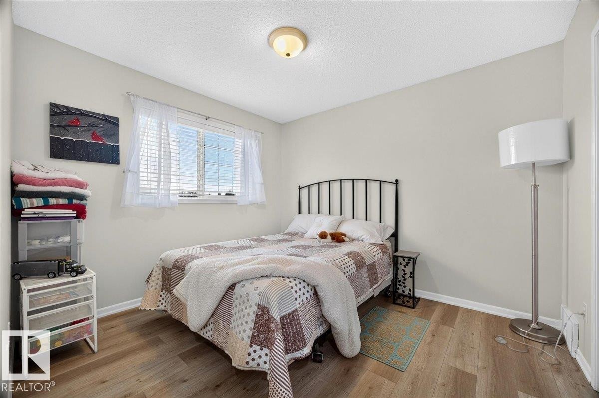 Bedroom featuring wood-finish flooring, neutral wall paint, and a window with blinds - 6 Norfolk Close, St. Albert, AB - Indoor Photo Showing Bedroom