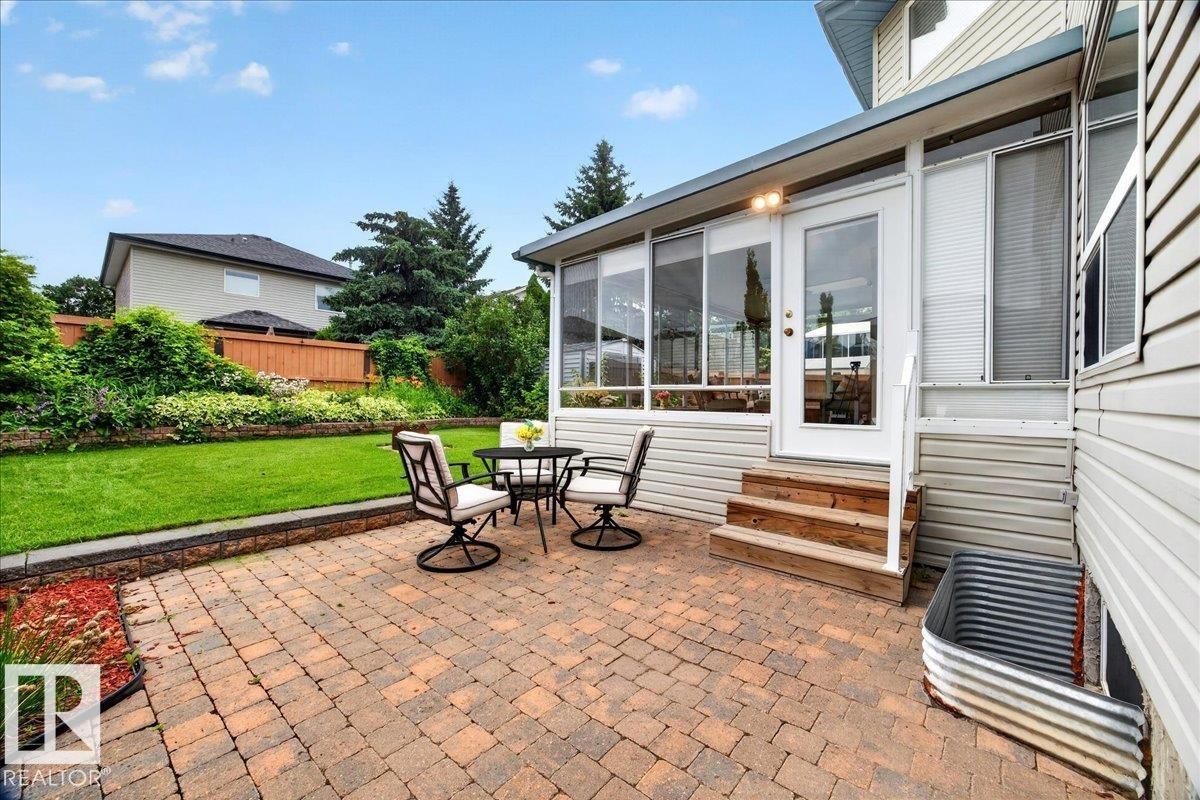 Paver patio with a stone retaining wall and a manicured lawn - 6 Norfolk Close, St. Albert, AB - Outdoor With Exterior