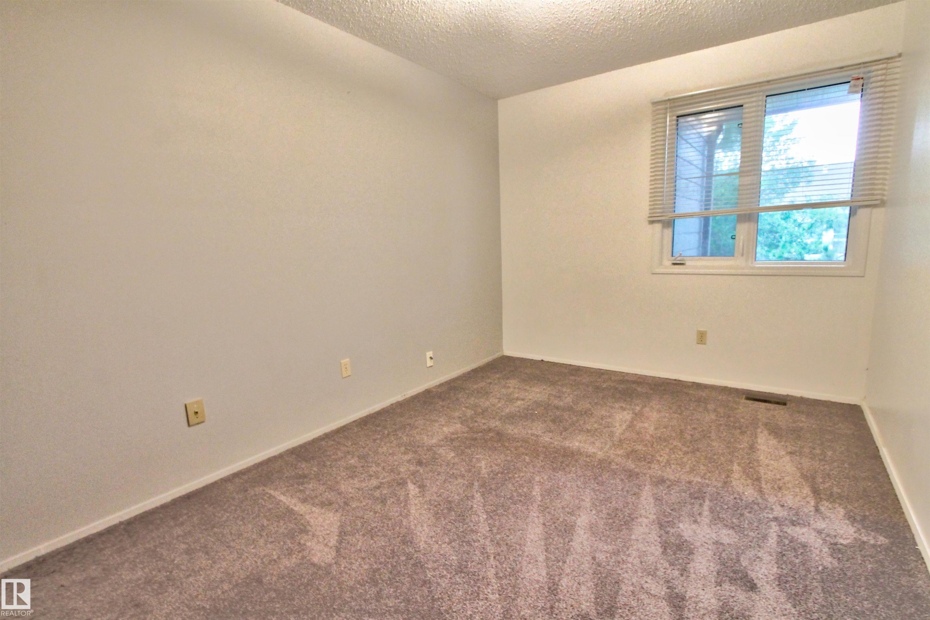Interior room featuring textured carpeting, white painted walls, and a window with horizontal blinds - #302 47 Akins Dr, St. Albert, AB - Indoor Photo Showing Other Room