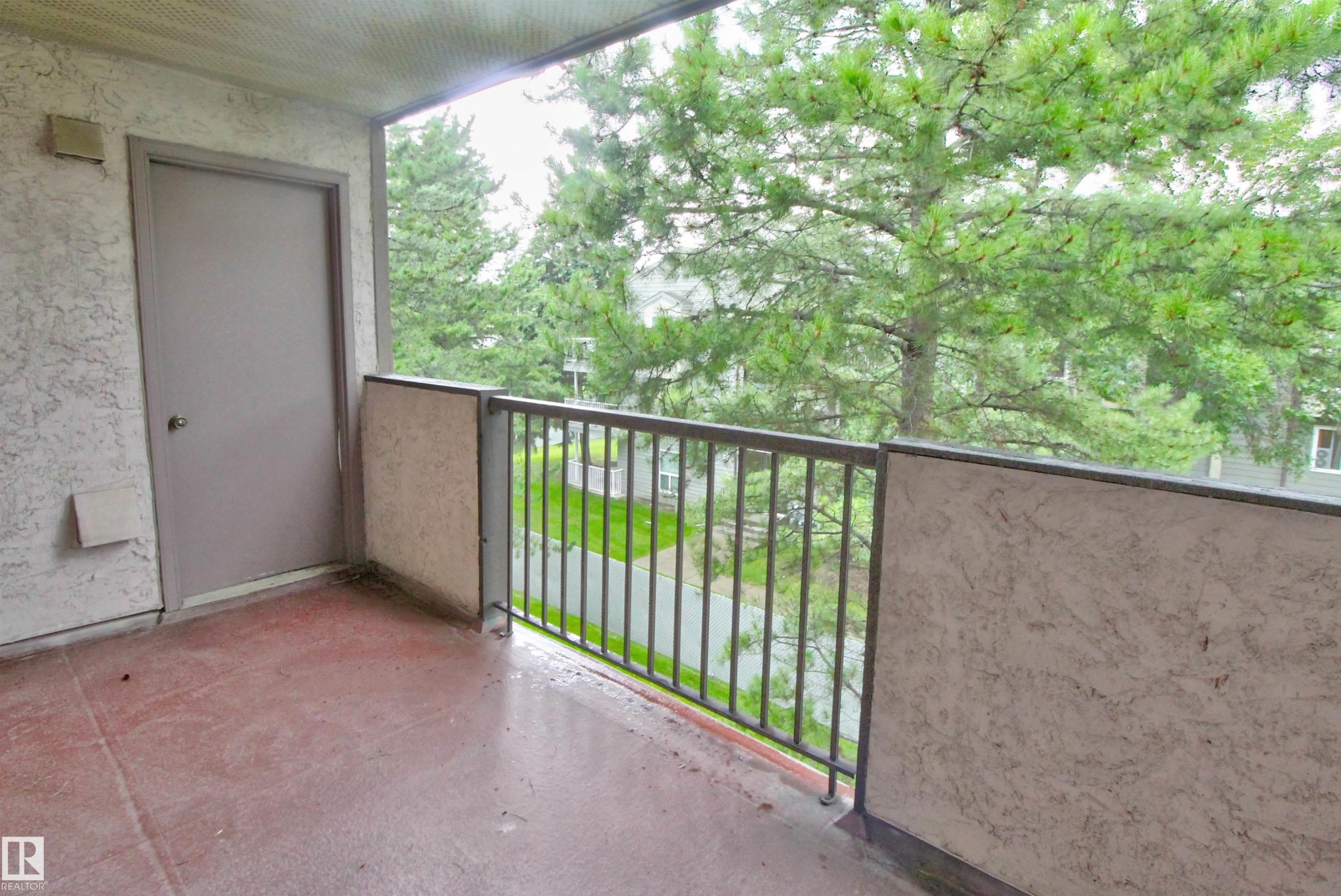 Private balcony featuring a textured wall finish, a neutral-toned door, and a metal railing - #302 47 Akins Dr, St. Albert, AB - Outdoor With Exterior