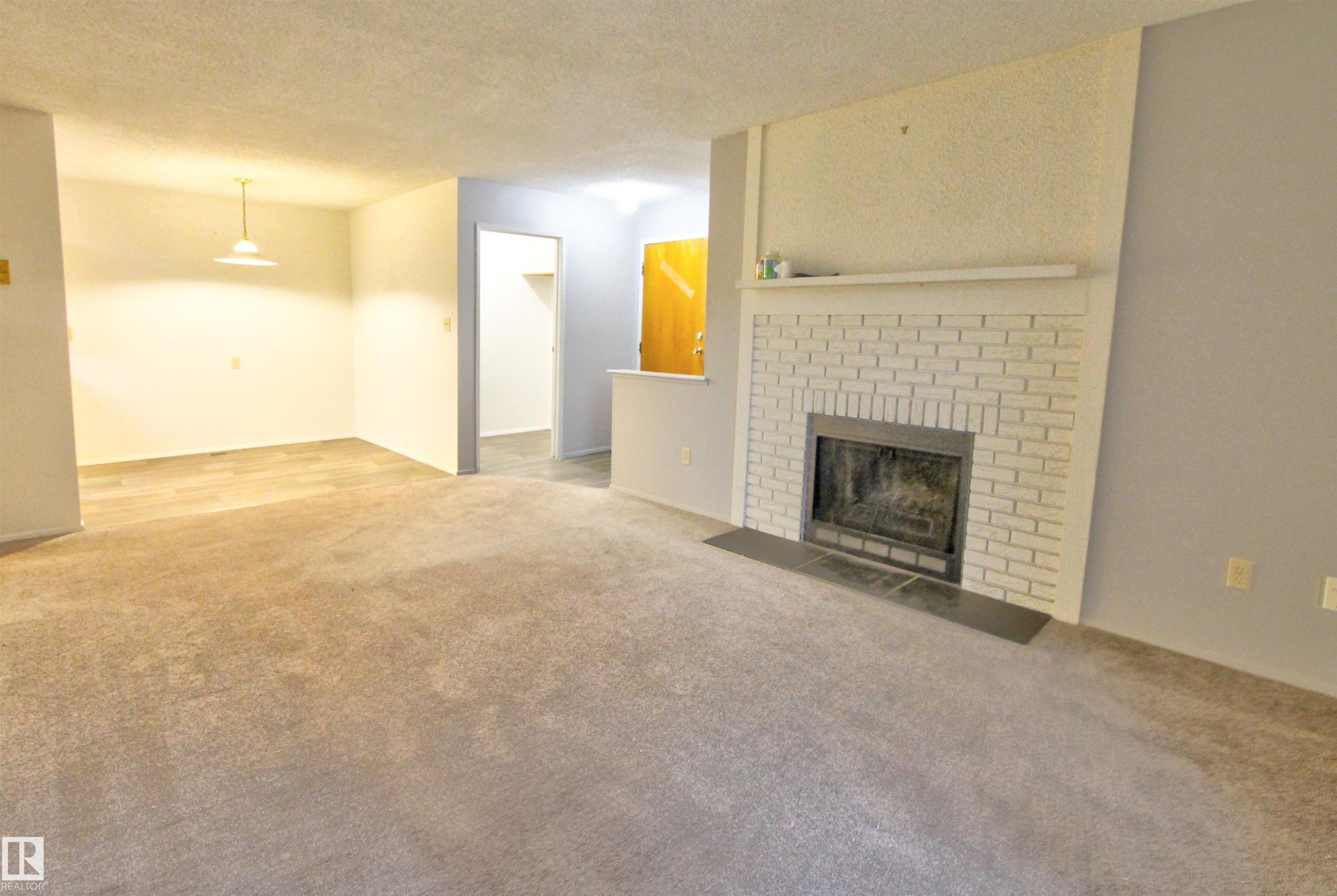 Living area featuring a white brick fireplace with a dark-toned hearth - #302 47 Akins Dr, St. Albert, AB - Indoor Photo Showing Living Room With Fireplace