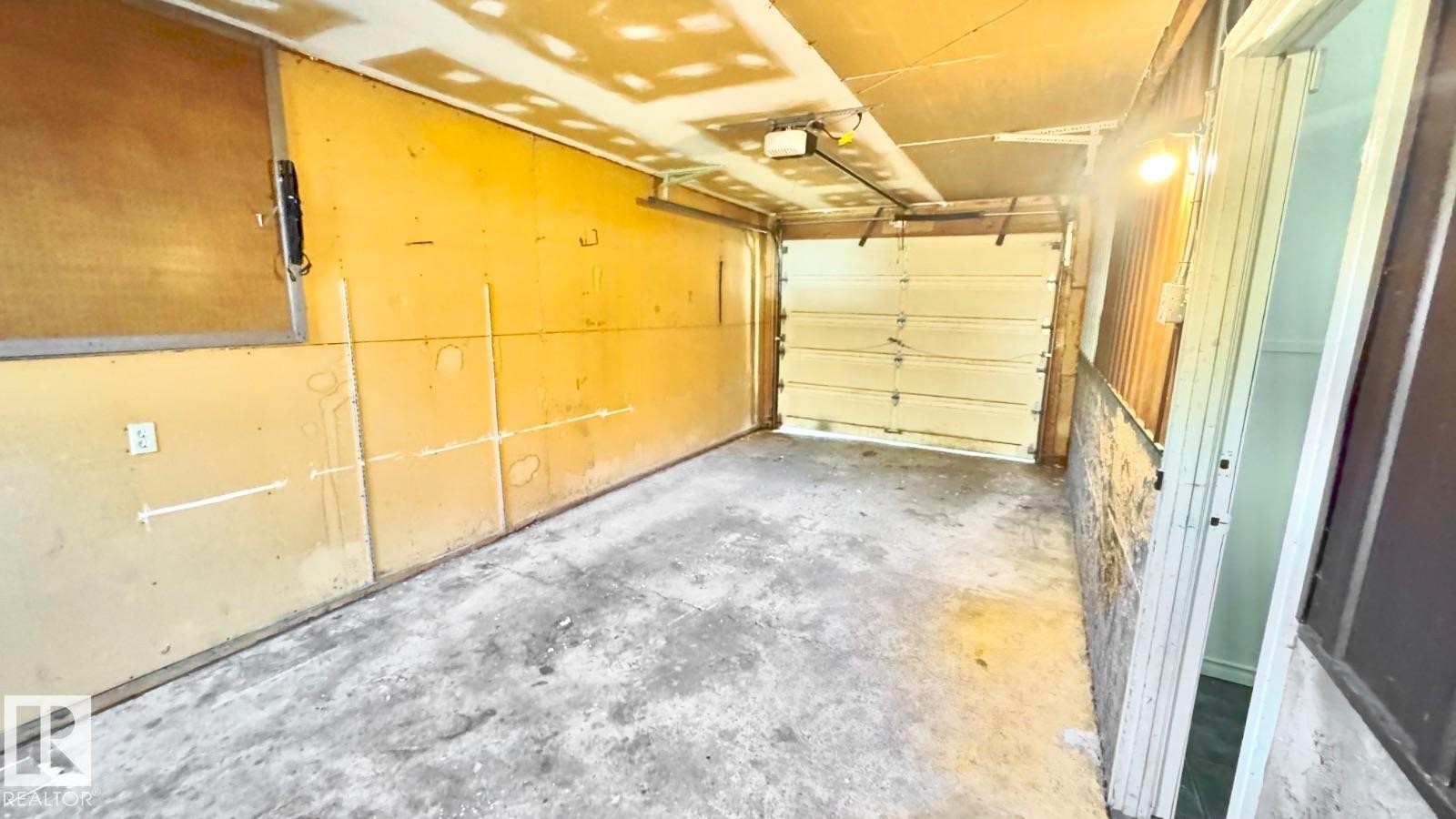 Spacious garage with exposed beam ceiling, concrete flooring, and a sectional overhead door - 5144 37 Avenue Nw, Edmonton, AB - Indoor Photo Showing Garage
