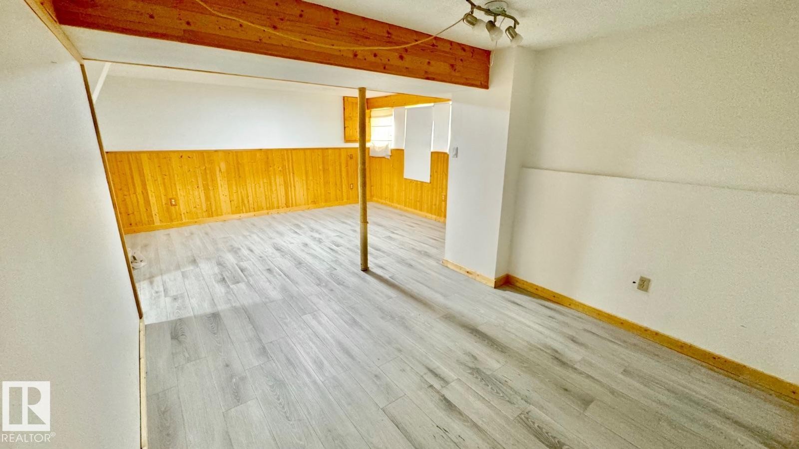 Spacious interior room featuring light wood-finish flooring, white walls, and wood paneling - 5144 37 Avenue Nw, Edmonton, AB - Indoor Photo Showing Other Room
