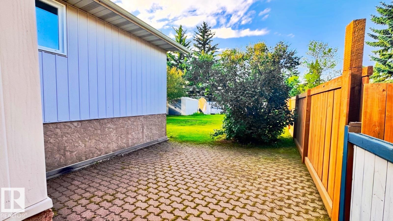 Patterned paver patio with a wooden fence and established greenery - 5144 37 Avenue Nw, Edmonton, AB - Outdoor