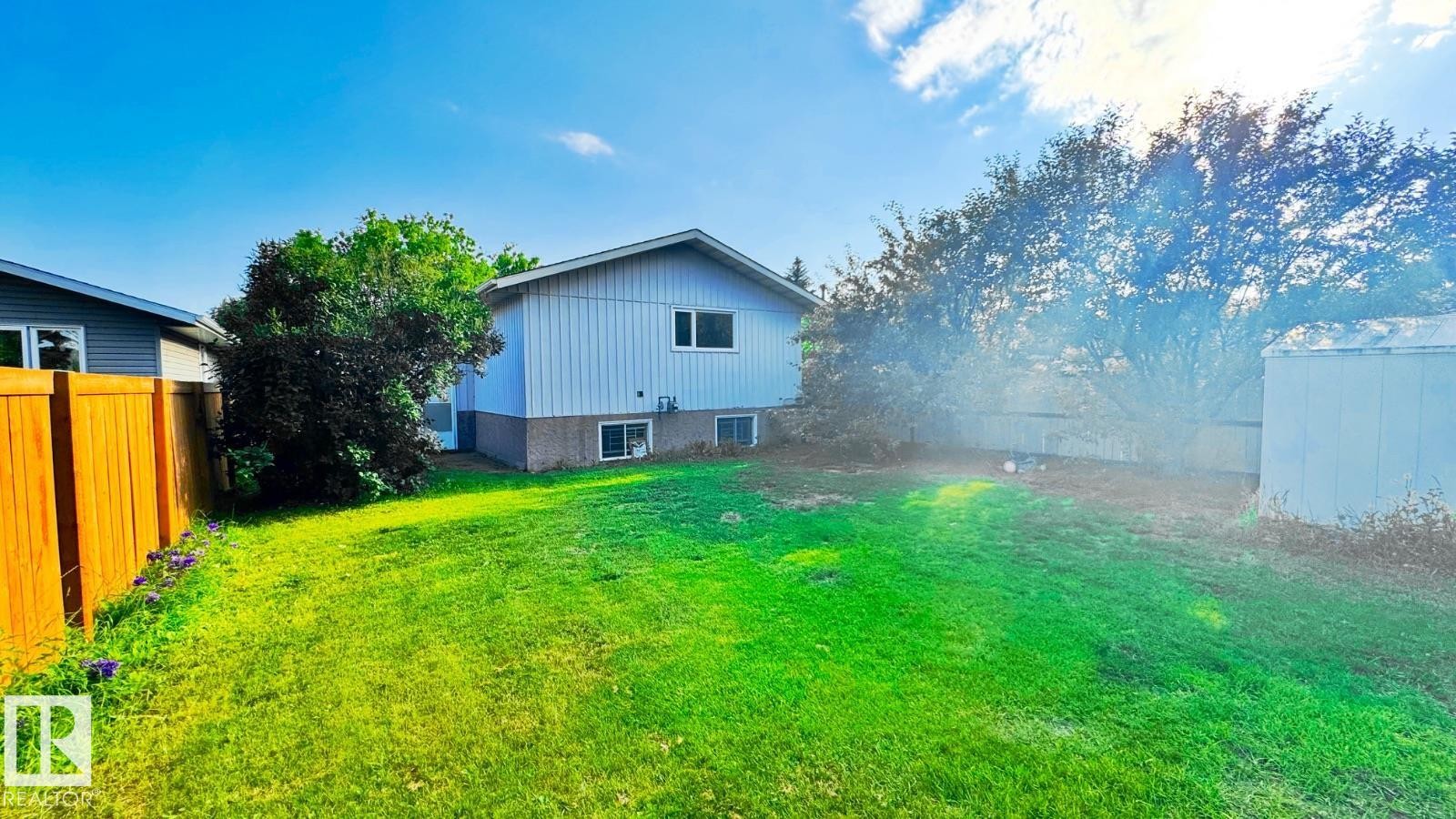Expansive rear yard featuring green lawn, mature trees, a wood privacy fence, and a storage shed - 5144 37 Avenue Nw, Edmonton, AB - Outdoor