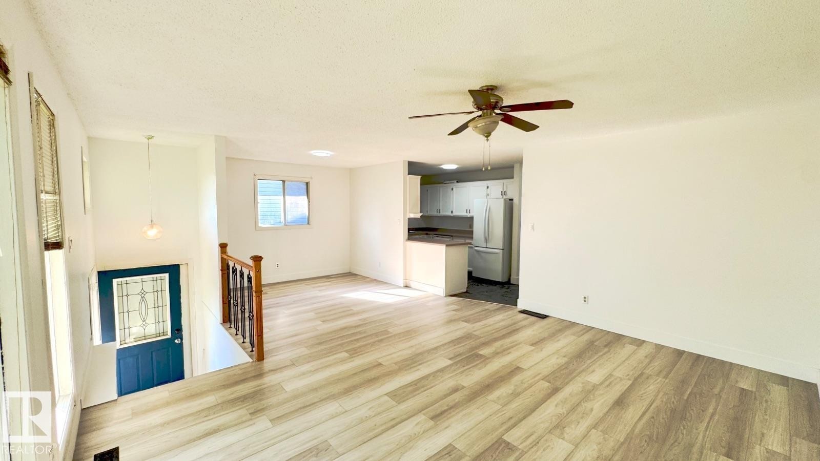 Open-concept living space featuring wood-finish flooring, a ceiling fan, and a kitchen visible in the background - 5144 37 Avenue Nw, Edmonton, AB - Indoor Photo Showing Other Room