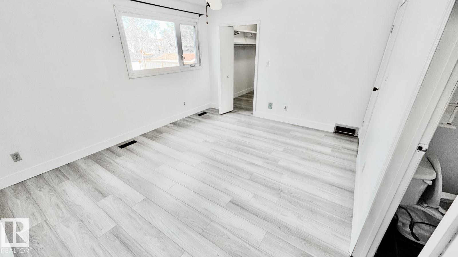 Spacious room featuring light wood-finish flooring, white baseboards, and a window with white trim - 5144 37 Avenue Nw, Edmonton, AB - Indoor Photo Showing Other Room
