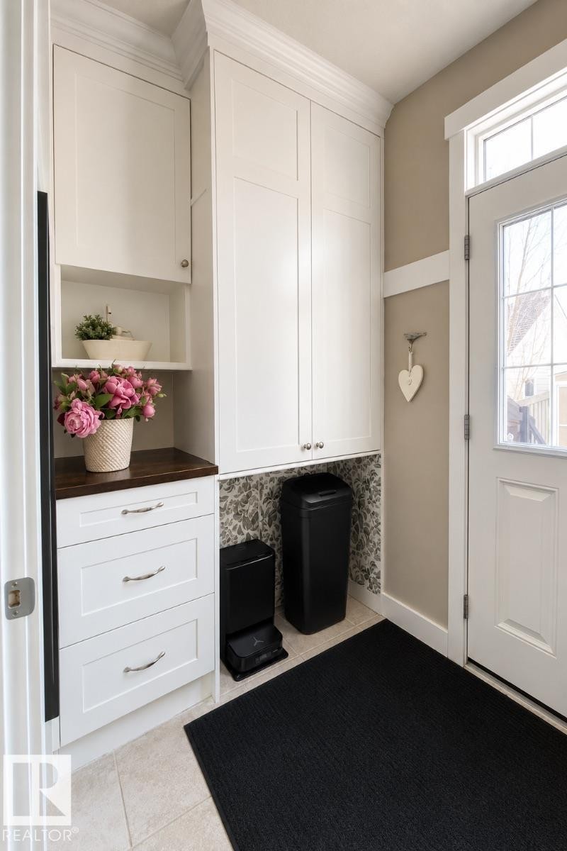Entryway featuring custom white cabinetry with crown molding, a dark wood-finish countertop, and tile flooring - 2337 Frezenberg Avenue Nw, Edmonton, AB - Indoor Photo Showing Other Room