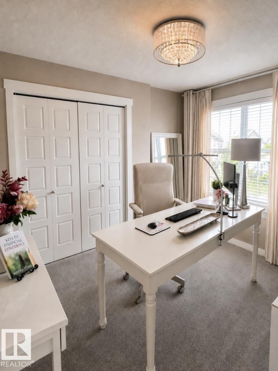 Plush carpeting and a contemporary drum chandelier illuminate this versatile room, featuring a window with blinds and full-length drapes, and paneled bi-fold doors - 2337 Frezenberg Avenue Nw, Edmonton, AB - Indoor Photo Showing Office