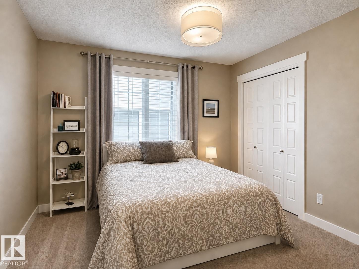 Carpeted room featuring a double-pane window with blinds and drapes, a drum-style ceiling light fixture, and a built-in bifold closet with white paneled doors - 2337 Frezenberg Avenue Nw, Edmonton, AB - Indoor Photo Showing Bedroom