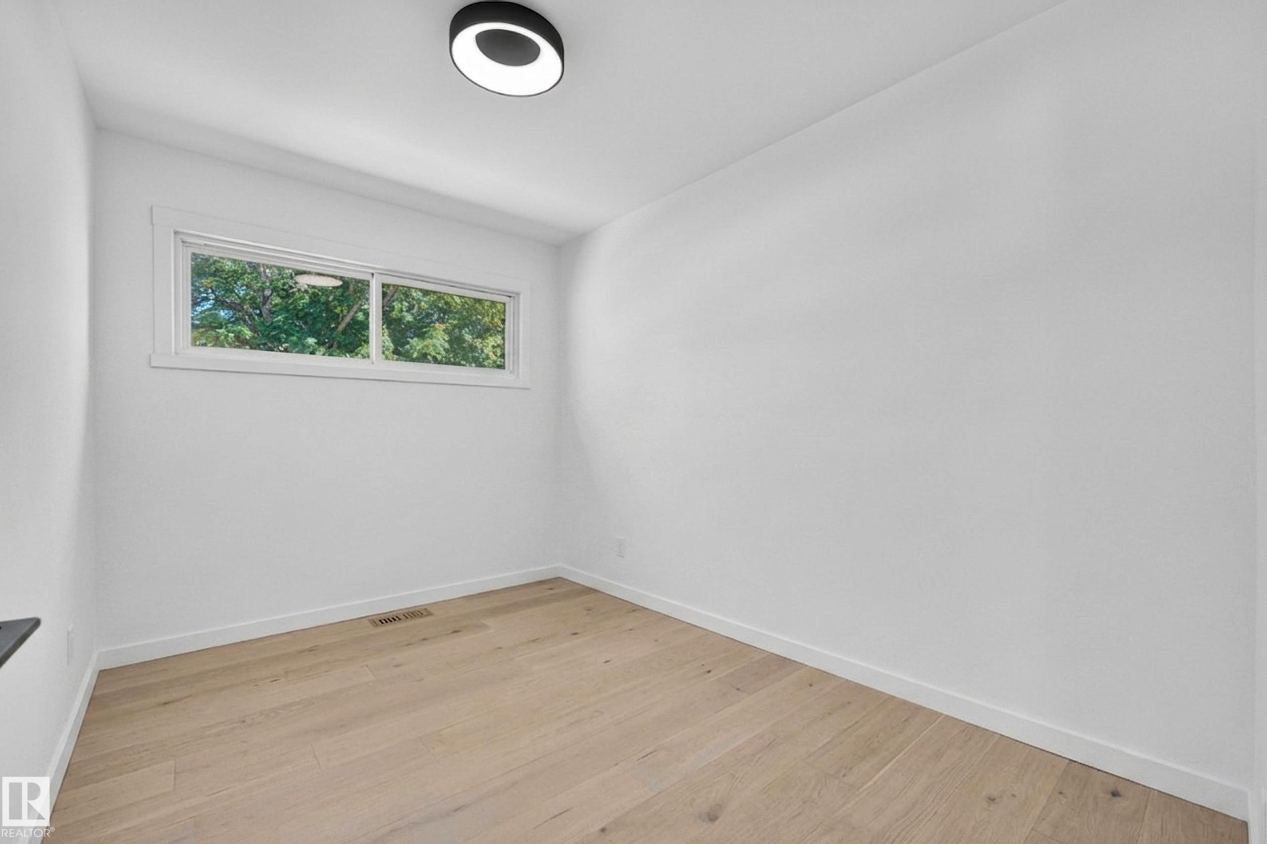 Bright room with light wood-finish flooring, white walls, and a modern ceiling light fixture - 6011 93A Avenue Nw, Edmonton, AB - Indoor Photo Showing Other Room