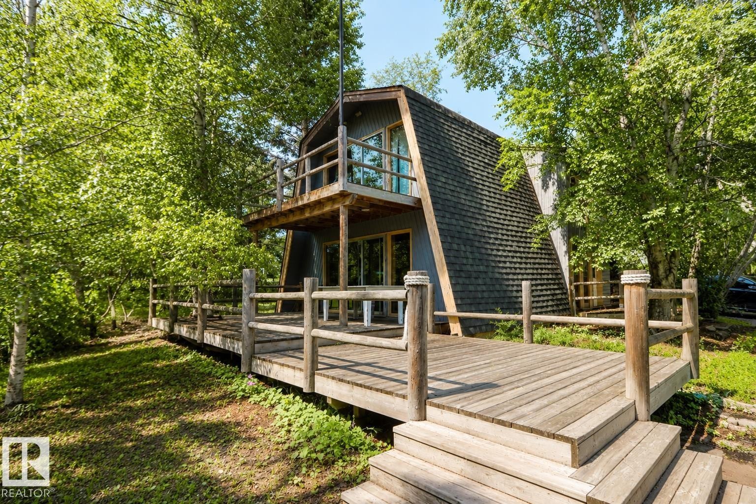 A-frame exterior featuring a shingled roof, a ground-level deck, and an upper-level balcony with wood railings - 329 60417 Range Road 124, Rural St. Paul County, AB - Outdoor With Deck Patio Veranda