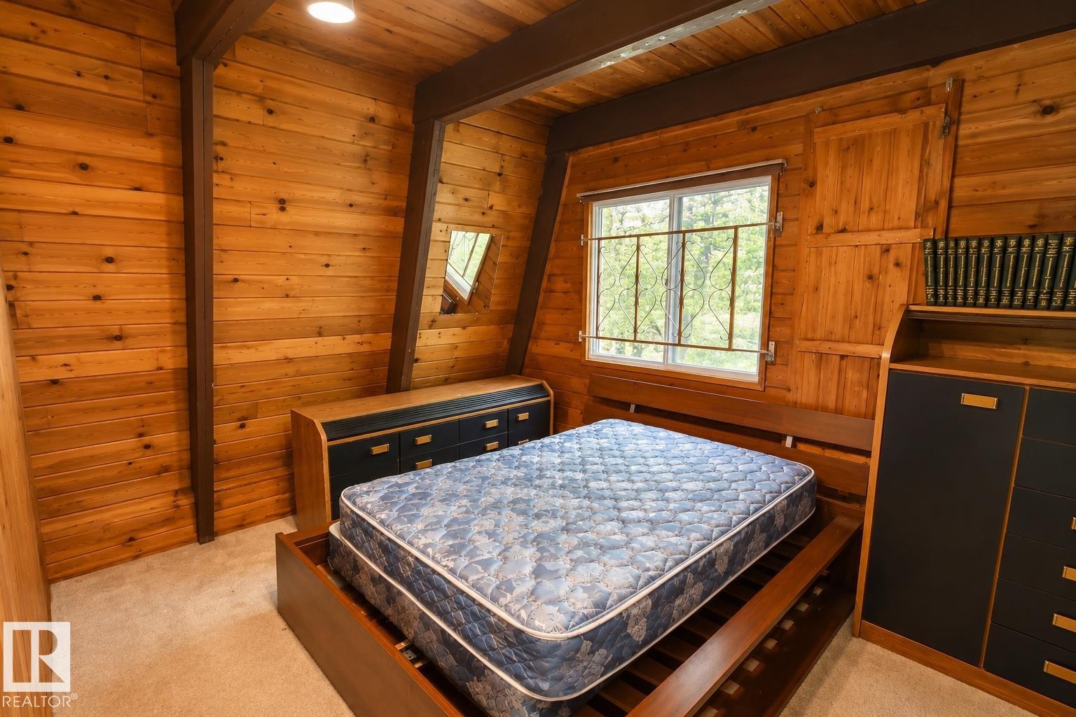 Interior room featuring natural wood paneling, exposed wood beams, and a window with security bars - 329 60417 Range Road 124, Rural St. Paul County, AB - Indoor Photo Showing Bedroom