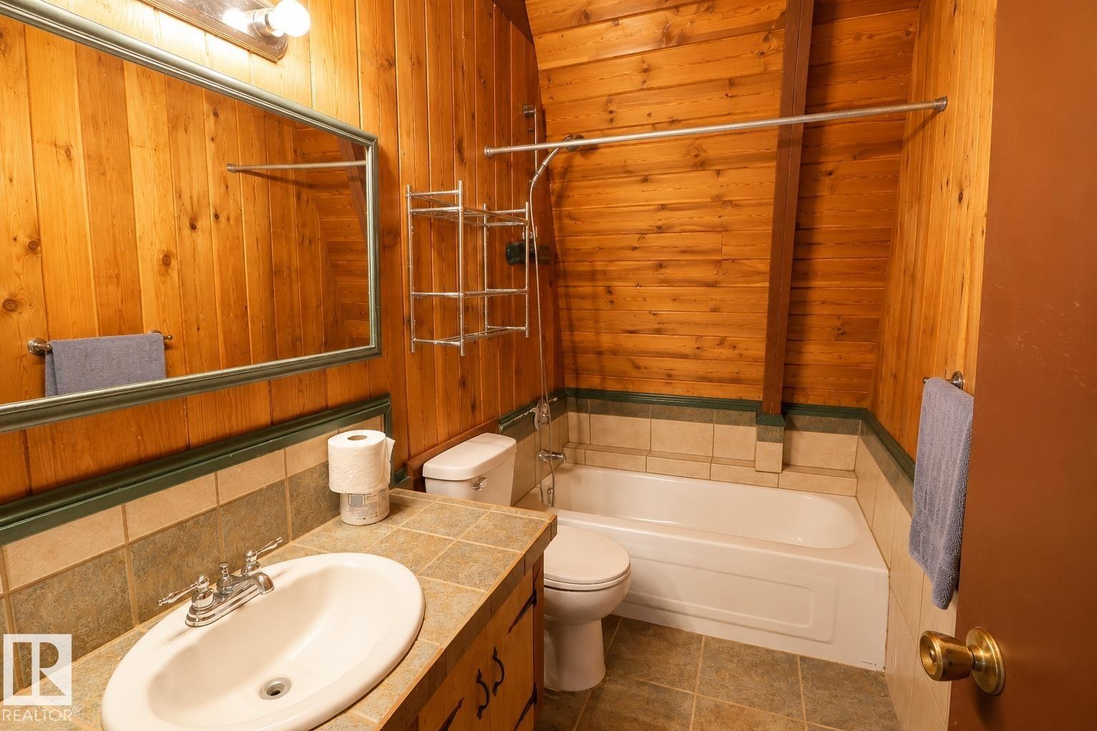 Bathroom featuring wood-paneled walls and a built-in vanity with an undermount sink - 329 60417 Range Road 124, Rural St. Paul County, AB - Indoor Photo Showing Bathroom