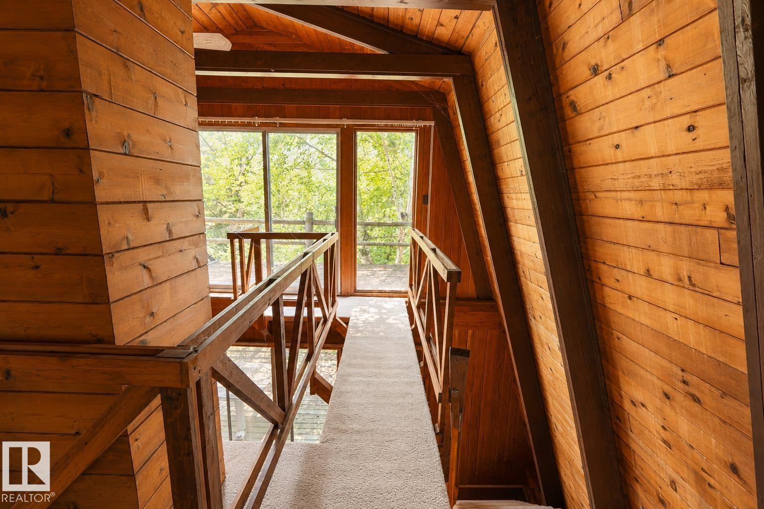Carpeted hallway with wood-paneled walls and ceiling, featuring a wood railing - 329 60417 Range Road 124, Rural St. Paul County, AB - Indoor Photo Showing Other Room