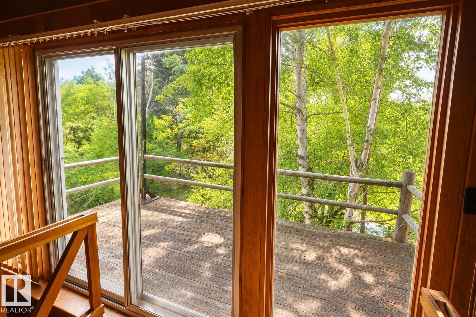 Sliding glass doors opening to an exterior wood-finish deck with a rustic wood railing - 329 60417 Range Road 124, Rural St. Paul County, AB - Indoor Photo Showing Other Room