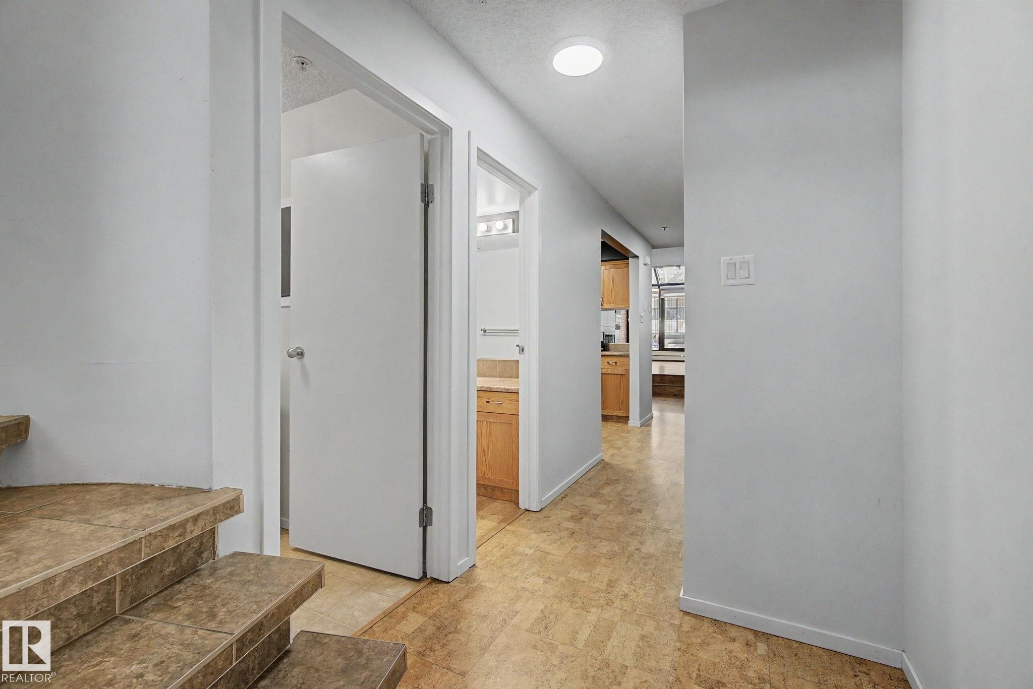 Entryway featuring tile flooring, white walls, recessed ceiling lighting, and a view into a bathroom with a wood-finish vanity - 11150 83 Avenue Nw, Edmonton, AB