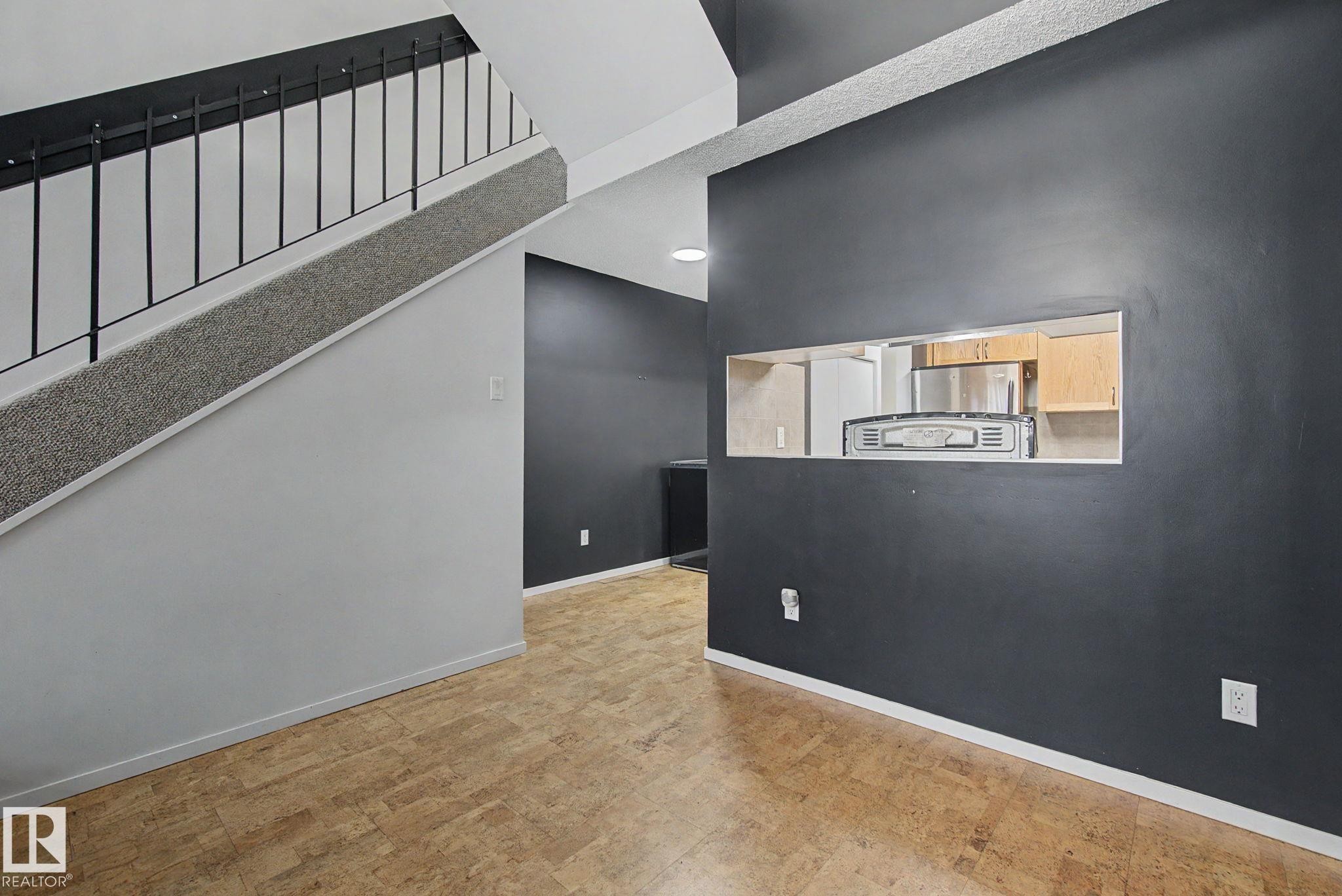 Wood-finish flooring throughout, featuring a staircase with carpeted treads and metal balusters - 11150 83 Avenue Nw, Edmonton, AB
