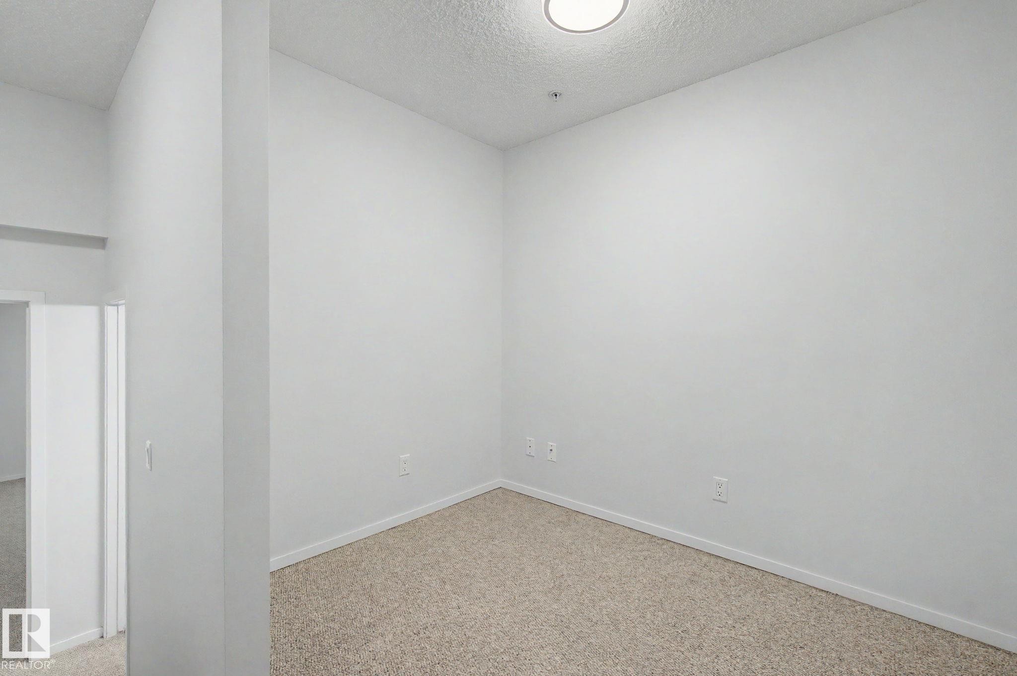 Bright interior space featuring light-toned carpeting and white baseboards - 11150 83 Avenue Nw, Edmonton, AB