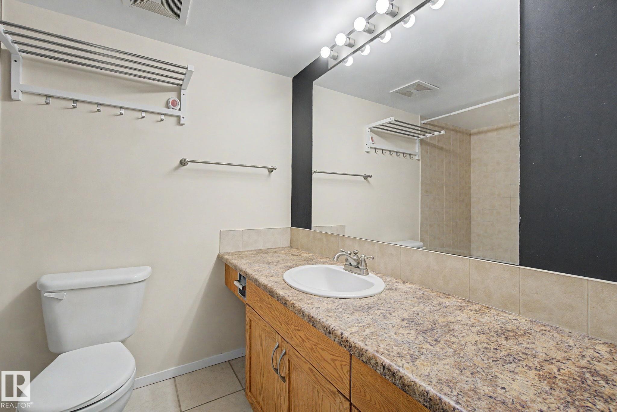 Bathroom vanity featuring an integrated sink, laminate countertop, and wood-finish cabinetry - 11150 83 Avenue Nw, Edmonton, AB