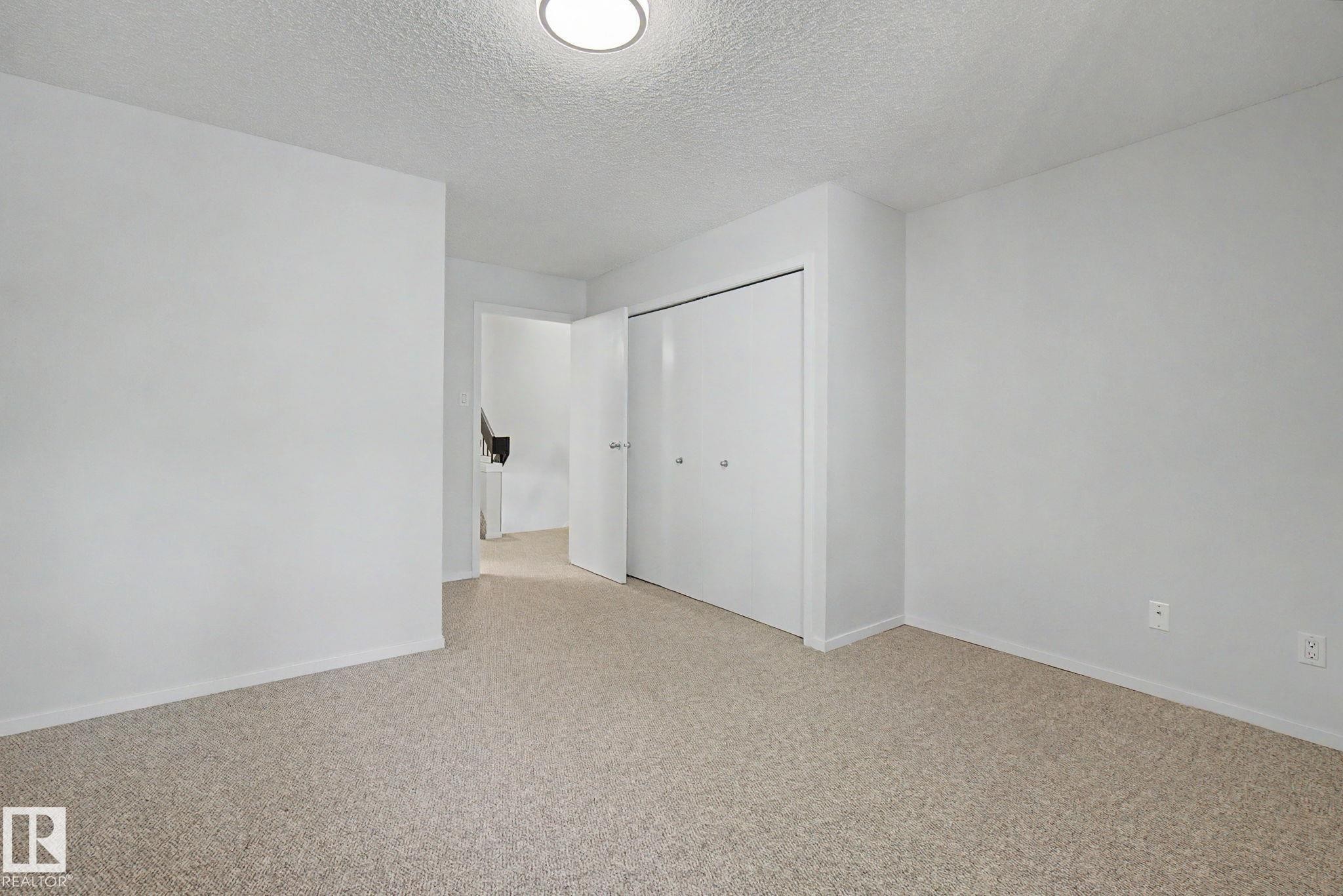 Bedroom featuring neutral tone carpeting and a closet with bi-fold doors - 11150 83 Avenue Nw, Edmonton, AB