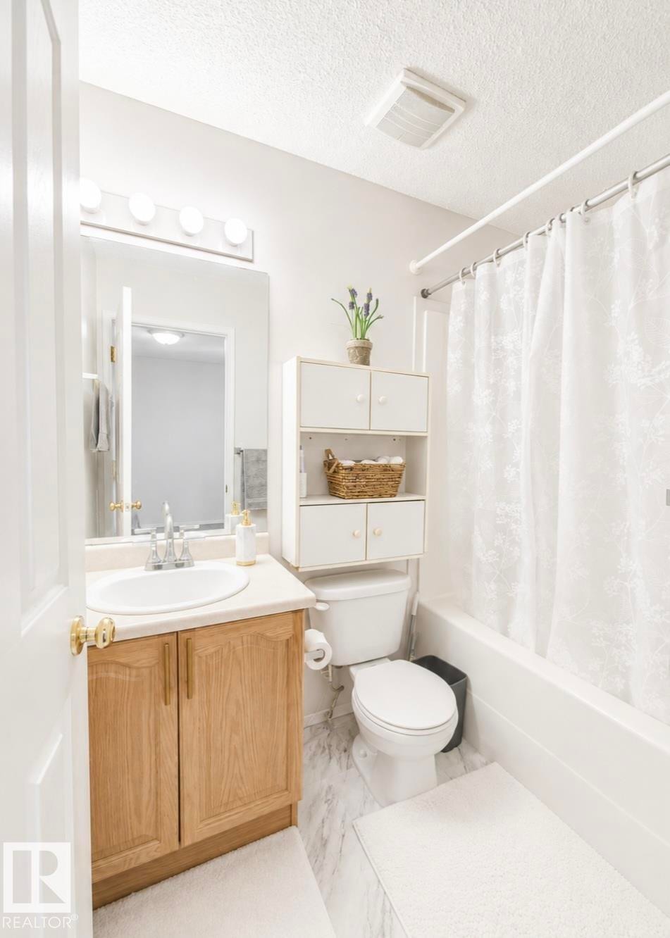 Vanity with wood-finish cabinetry, integrated sink, and laminate countertop - 3236 27 Avenue Nw, Edmonton, AB - Indoor Photo Showing Bathroom