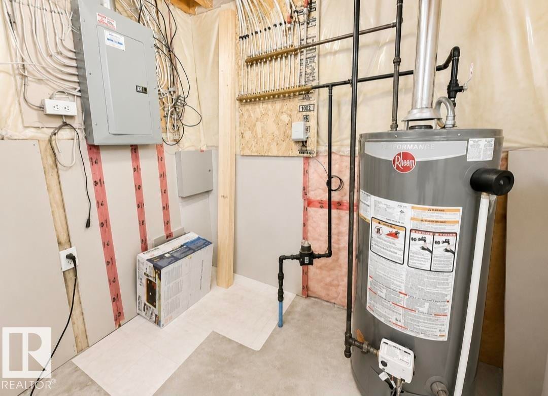 Utility area featuring a Rheem water heater, electrical panel, PEX manifold system, and concrete flooring - 3236 27 Avenue Nw, Edmonton, AB - Indoor Photo Showing Basement