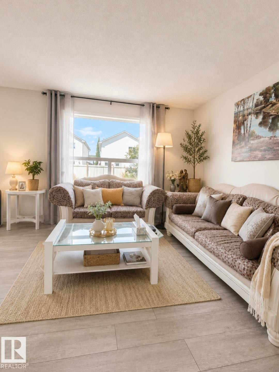 Light wood-finish flooring, white painted walls, and a large window with sheer and blackout curtains - 3236 27 Avenue Nw, Edmonton, AB - Indoor Photo Showing Living Room