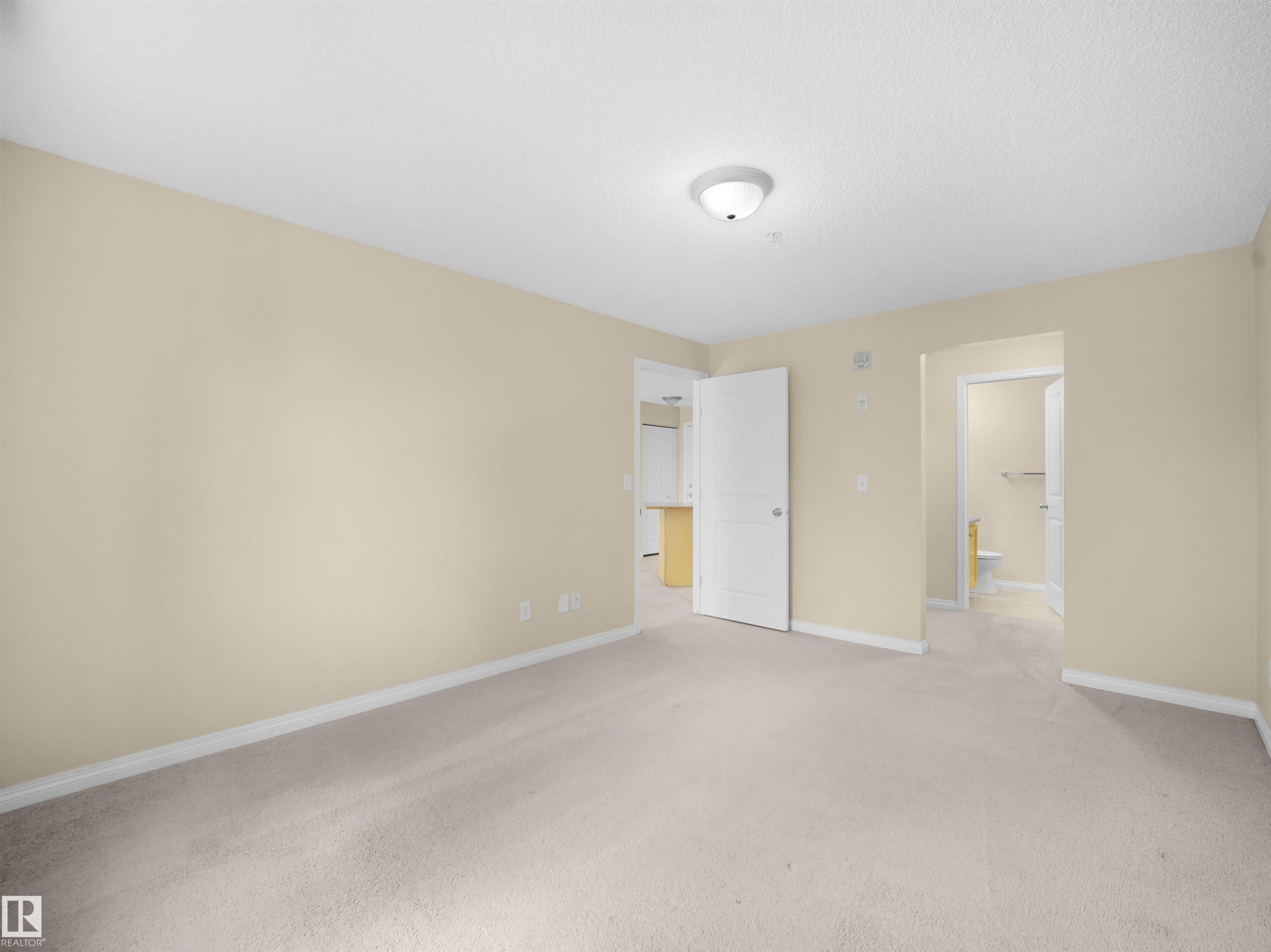 Carpeted interior space with light-toned walls and white trim - #220 245 Edwards Dr Sw, Edmonton, AB - Indoor Photo Showing Other Room