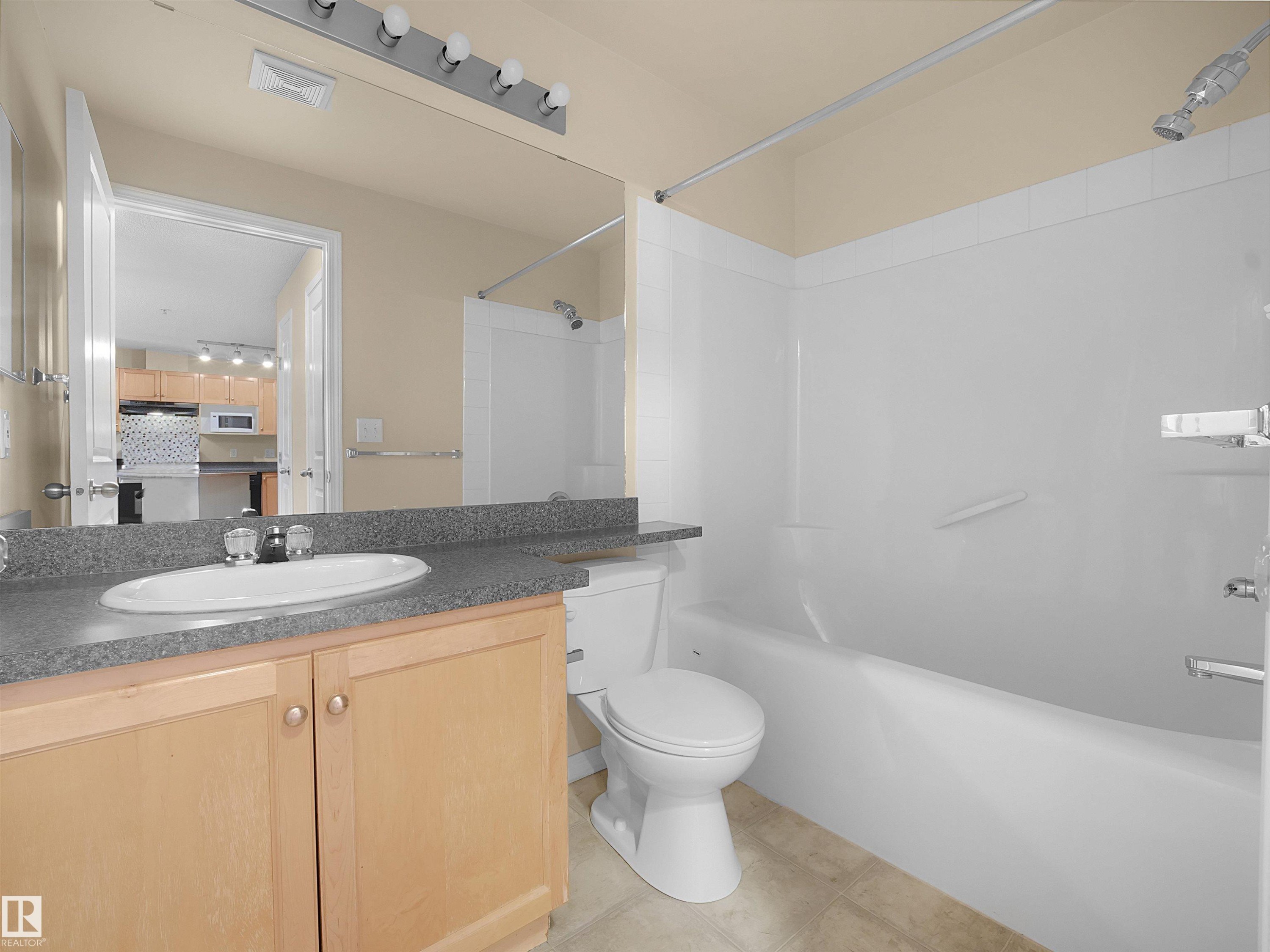 Bathroom featuring a light wood-finish vanity with a laminate countertop, an oval undermount sink, and a chrome faucet - #220 245 Edwards Dr Sw, Edmonton, AB - Indoor Photo Showing Bathroom