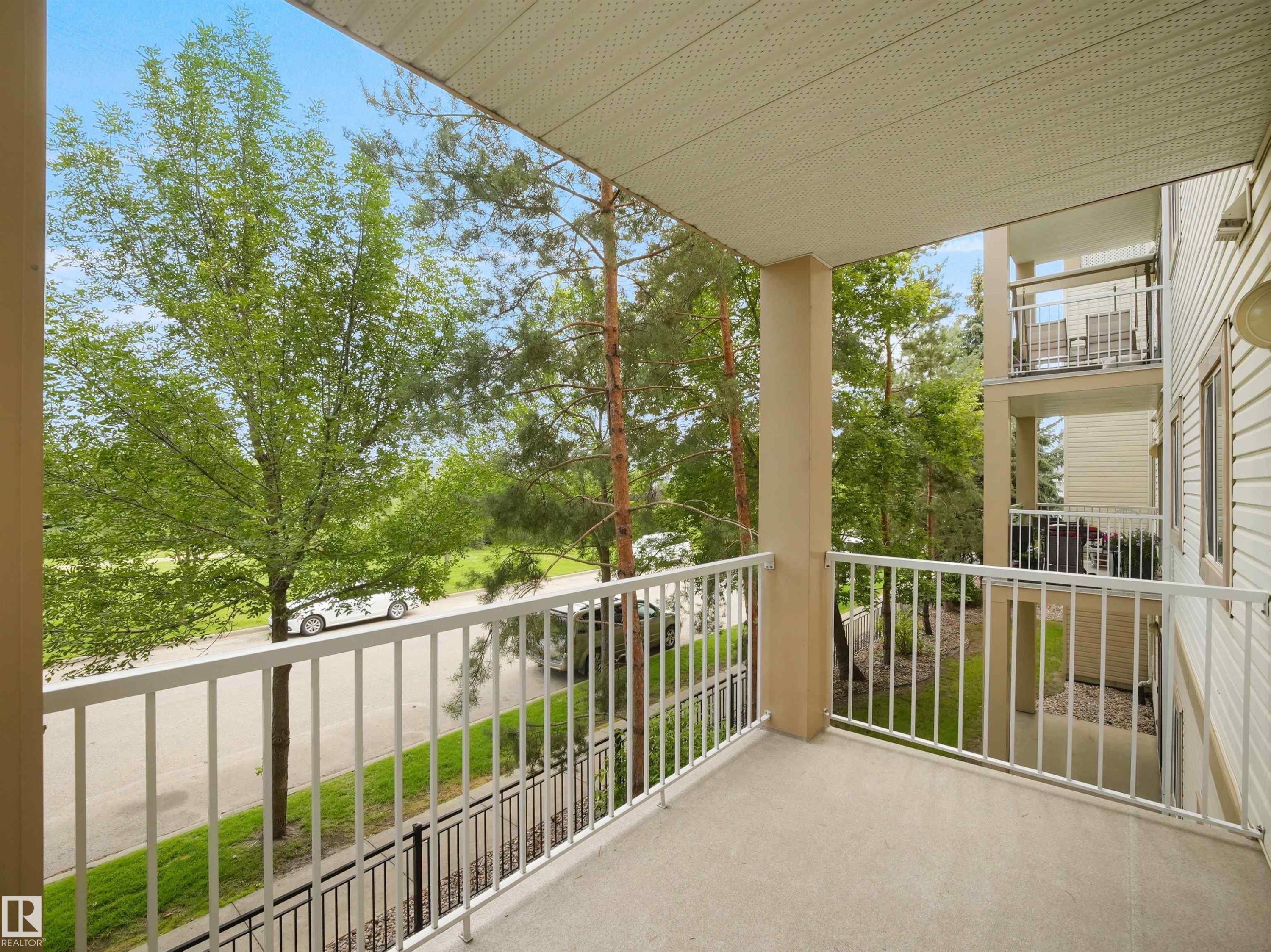 Private balcony featuring a textured concrete surface and white metal railings - #220 245 Edwards Dr Sw, Edmonton, AB - Outdoor With Balcony With Exterior