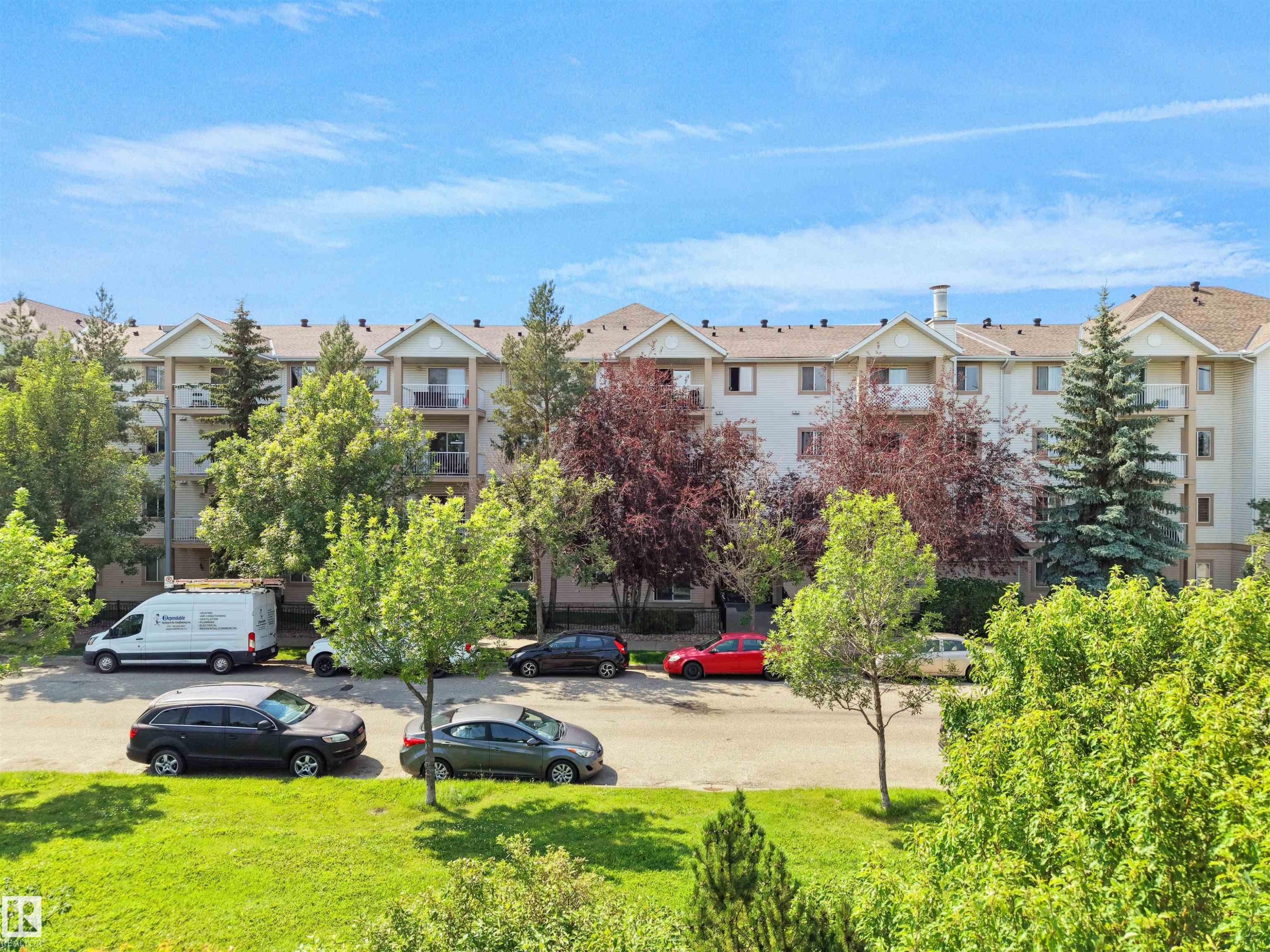 Multi-story residential building with light-toned siding and multiple balconies - #220 245 Edwards Dr Sw, Edmonton, AB - Outdoor