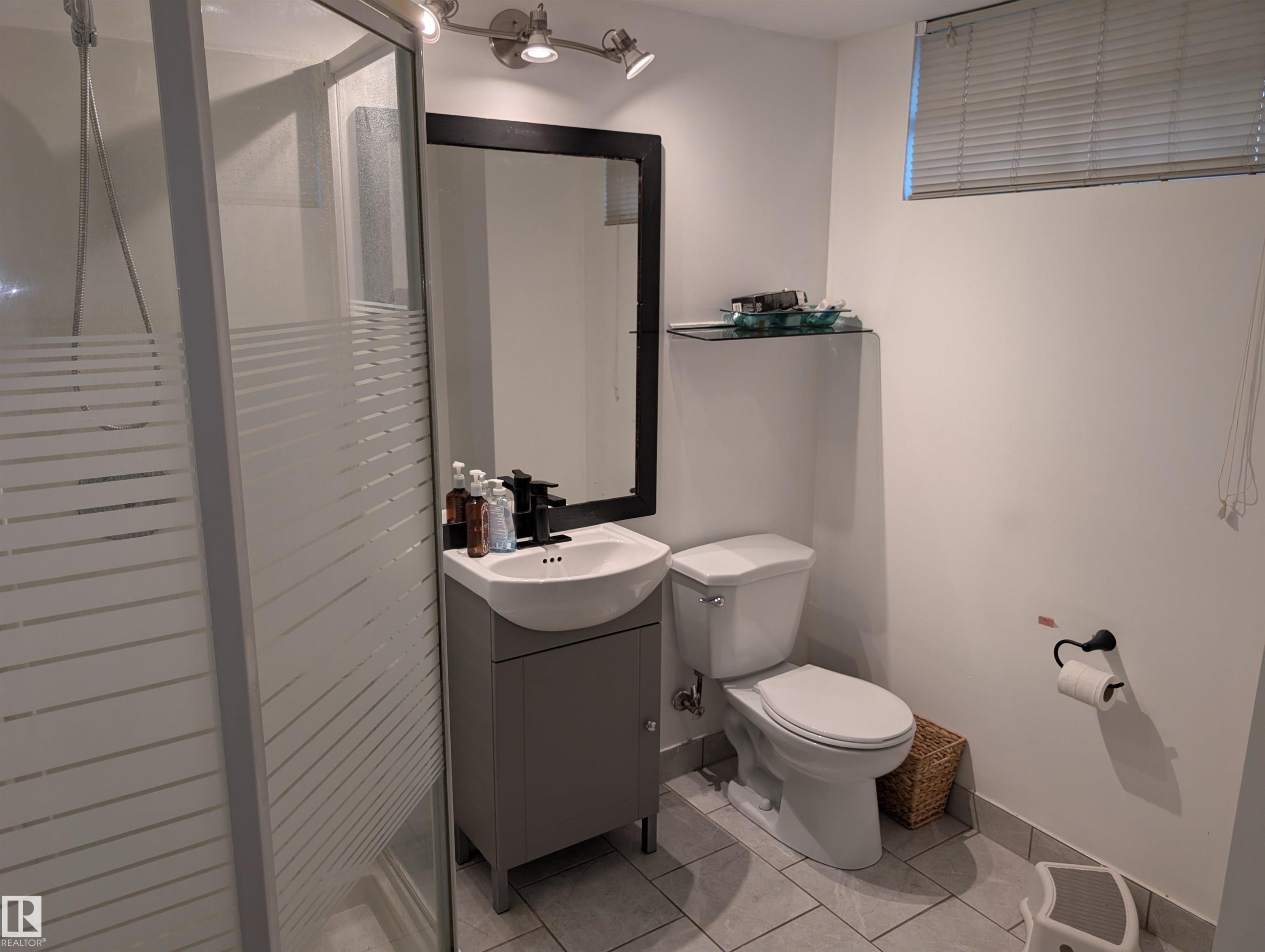 Compact bathroom featuring a glass-enclosed shower, a modern vanity with integrated sink, a sleek black-framed mirror, and track lighting - 14228 22 Street Nw, Edmonton, AB - Indoor Photo Showing Bathroom