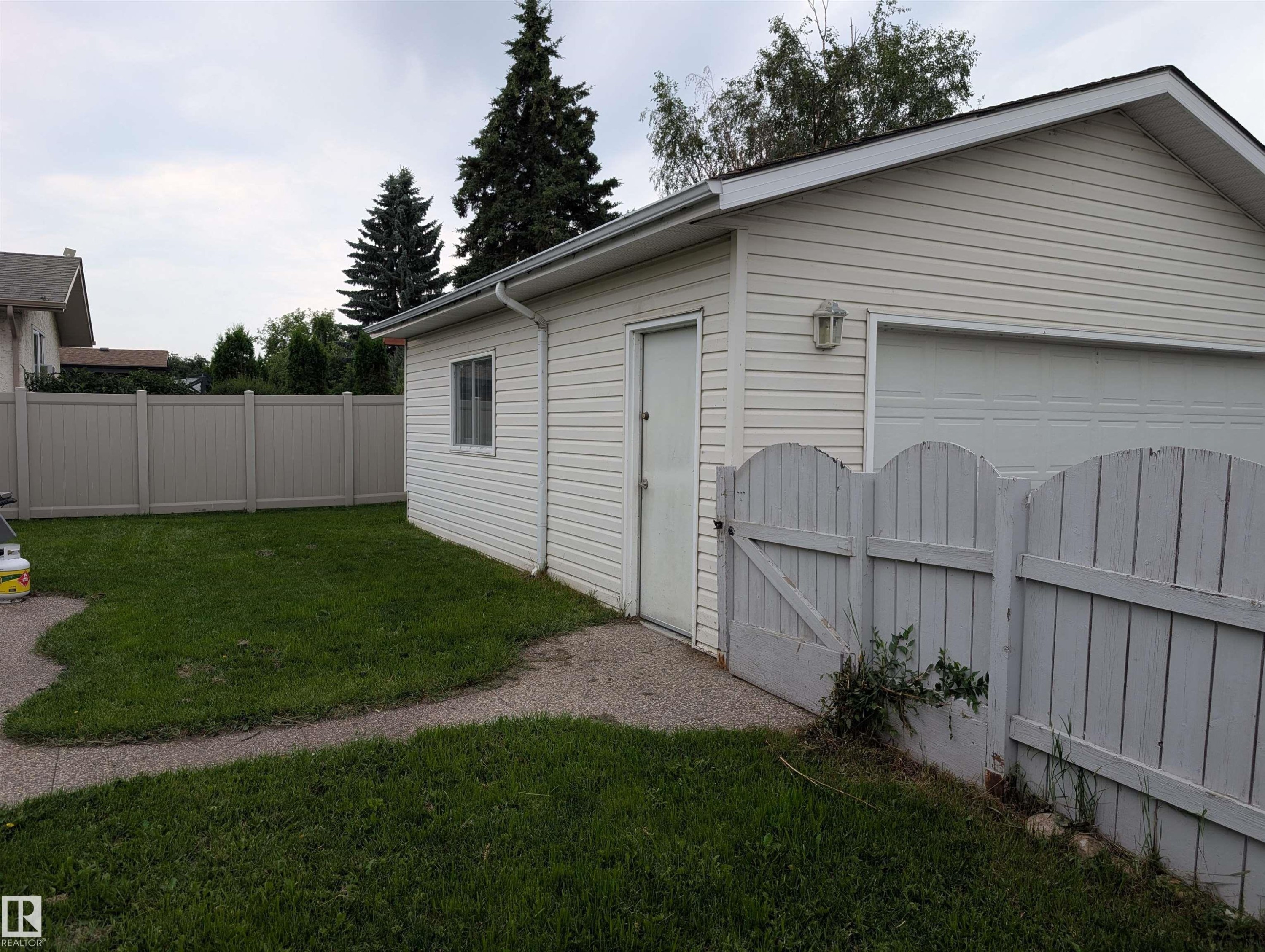 Detached garage with white siding, an overhead garage door, and a side entry door - 14228 22 Street Nw, Edmonton, AB - Outdoor