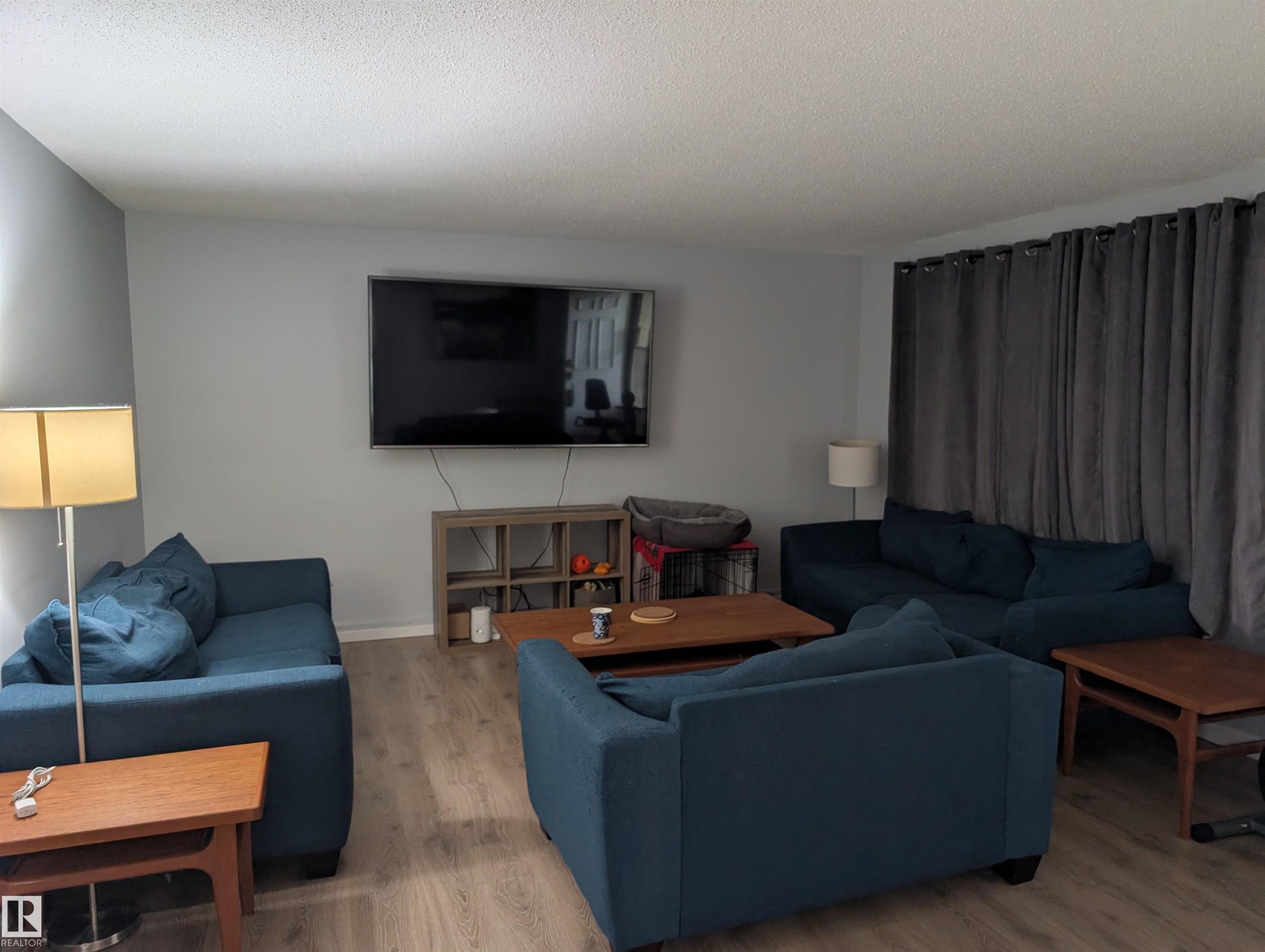 Living area featuring light gray walls, wood-finish flooring, and a mounted television - 14228 22 Street Nw, Edmonton, AB - Indoor Photo Showing Living Room