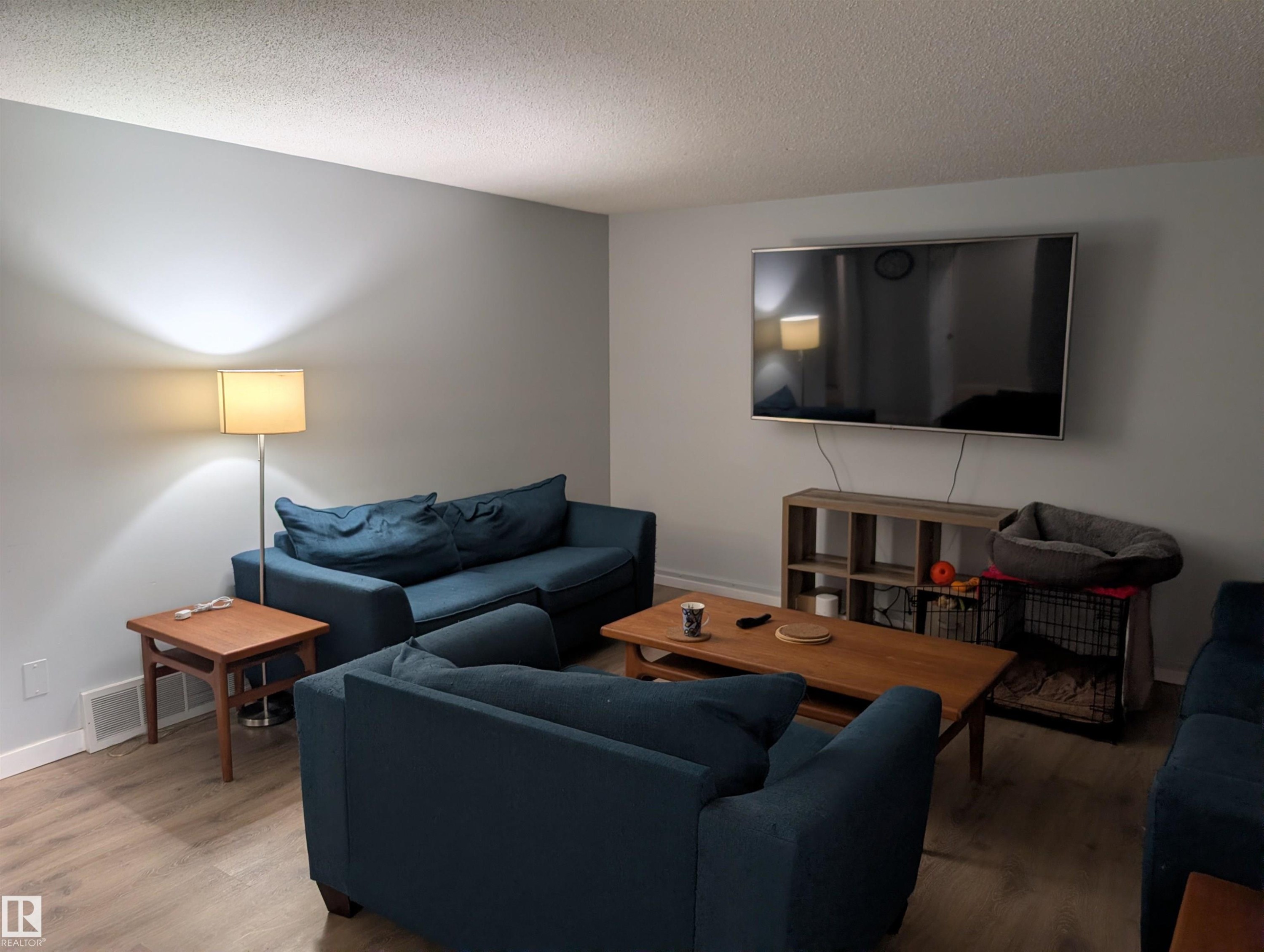 Spacious living area featuring light-toned wall paint and wood-finish flooring - 14228 22 Street Nw, Edmonton, AB - Indoor Photo Showing Living Room