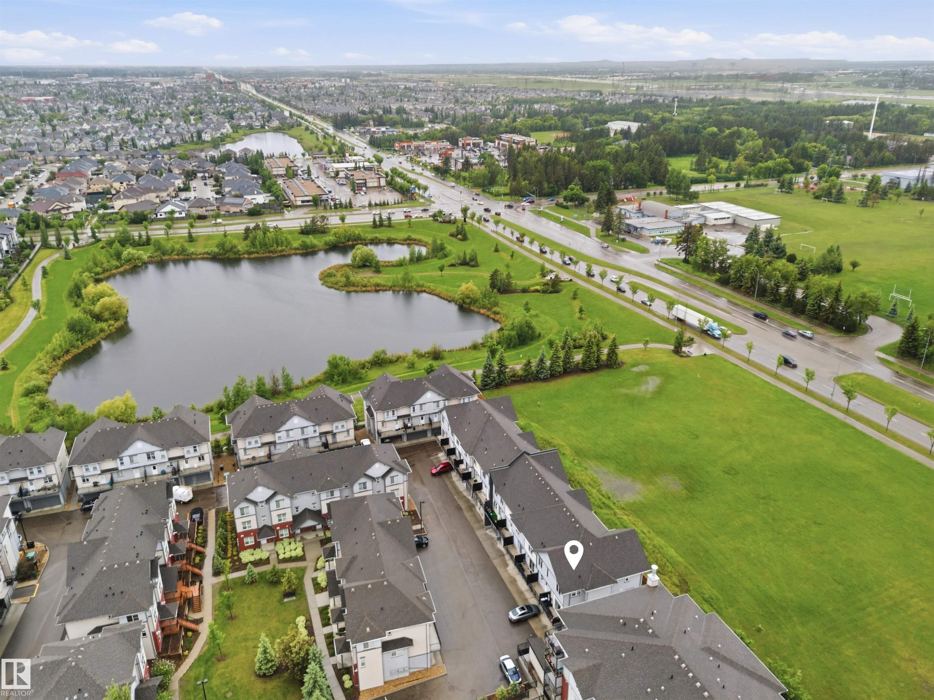 Aerial perspective showcasing a residential development with structured streetscapes - #64 655 Watt Bv Sw, Edmonton, AB - Outdoor With Body Of Water With View