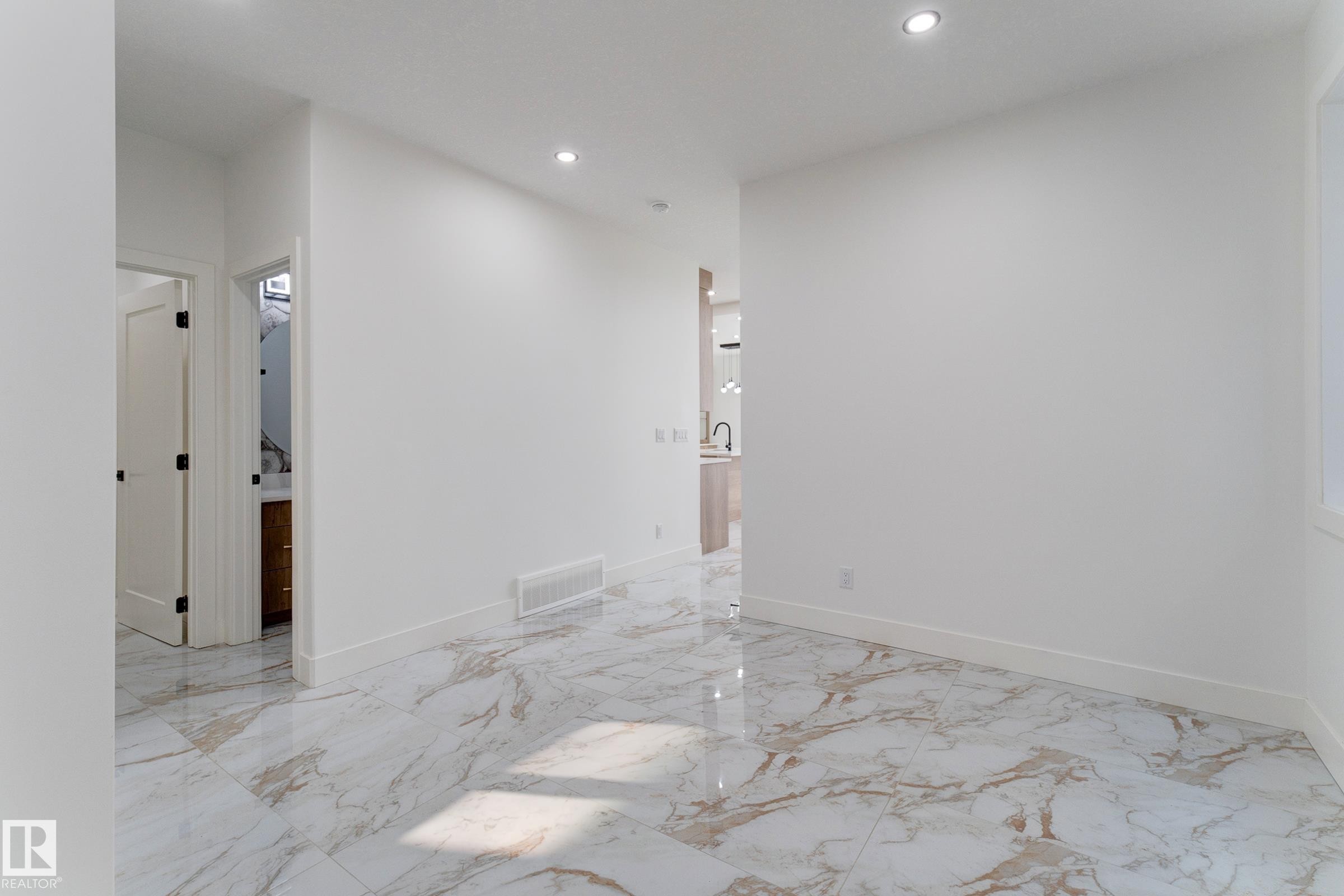Spacious room featuring large format marble-look tile flooring, white baseboards, recessed ceiling lighting, and a white interior door with dark hardware - 4723 17 Avenue Sw, Edmonton, AB - Indoor Photo Showing Other Room