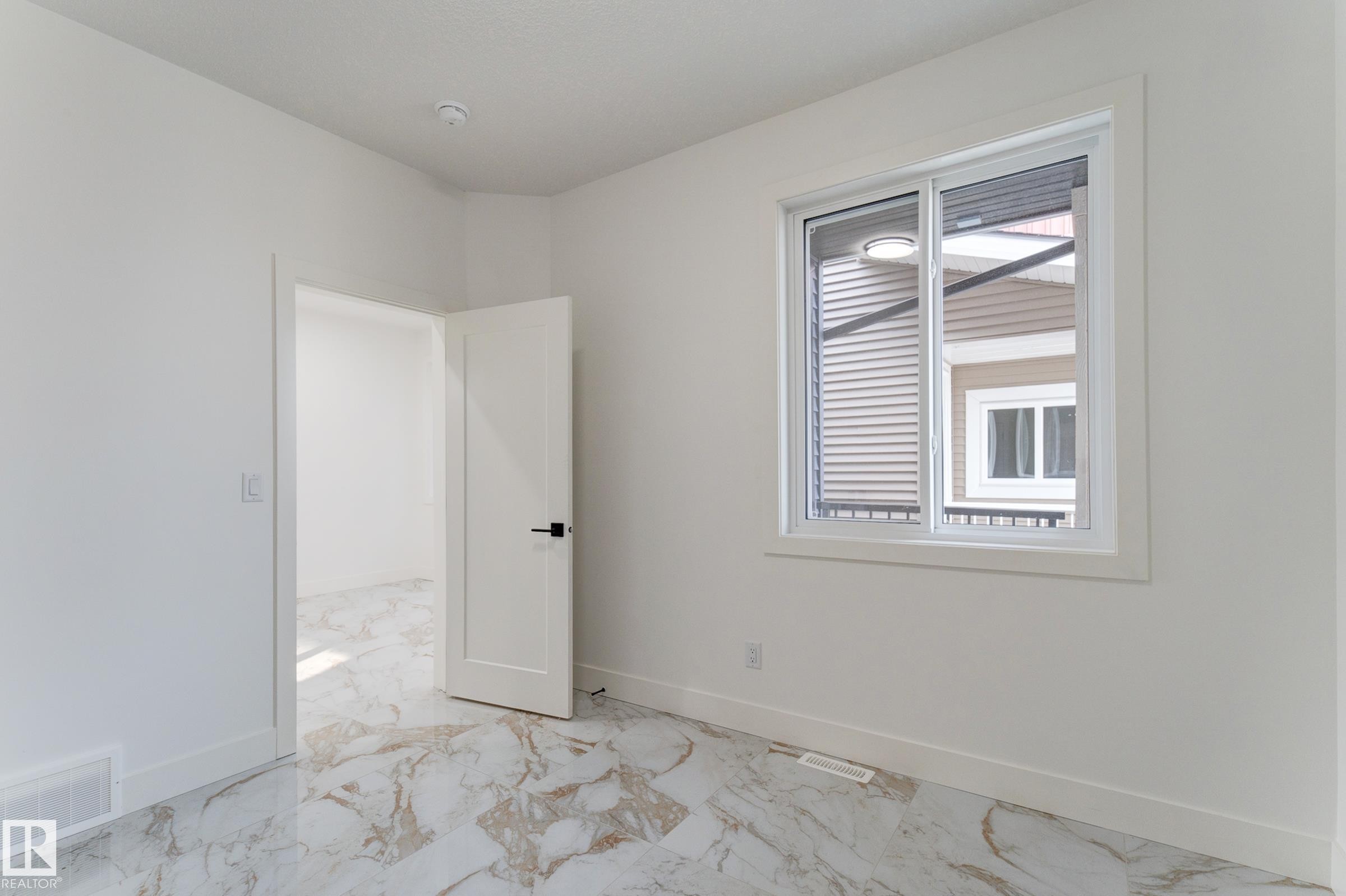 Spacious interior room featuring white walls, white baseboards, and elegant marble-look tile flooring - 4723 17 Avenue Sw, Edmonton, AB - Indoor