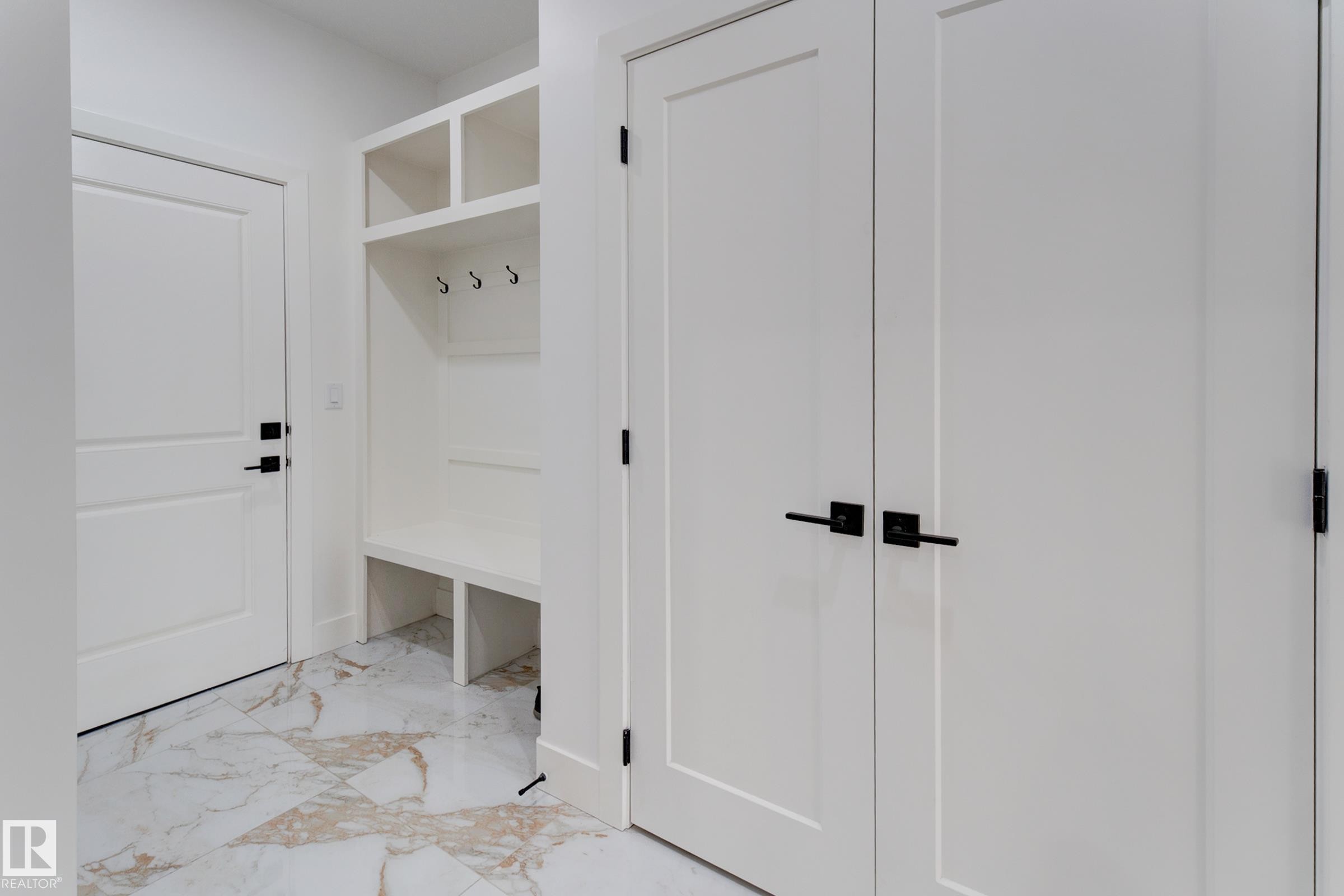 Built-in mudroom bench with upper cubbies and coat hooks, complemented by white panel doors with matte black hardware - 4723 17 Avenue Sw, Edmonton, AB - Indoor Photo Showing Other Room