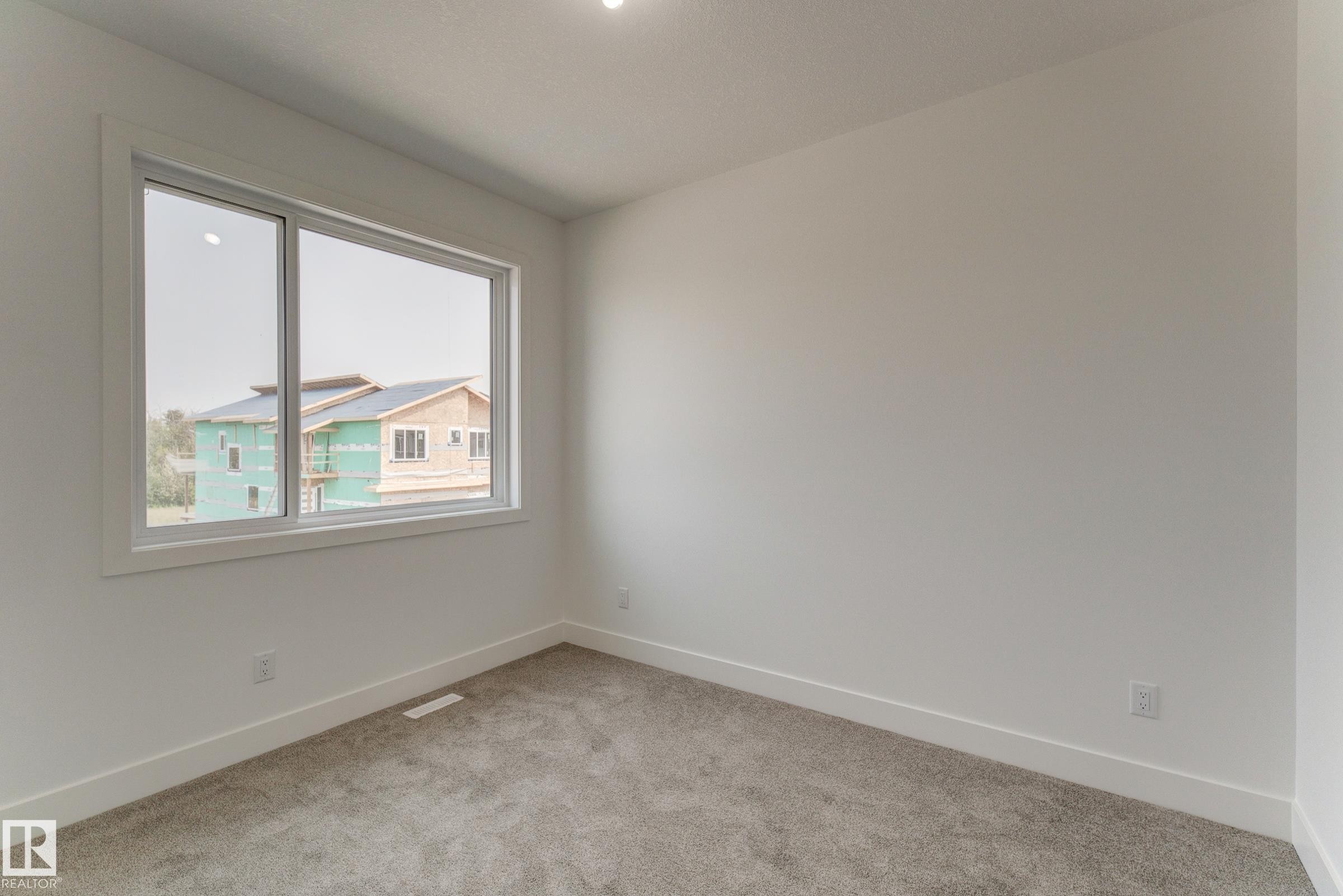 Bright room featuring a large window, plush gray carpet, white walls, and clean white baseboards - 4723 17 Avenue Sw, Edmonton, AB - Indoor Photo Showing Other Room