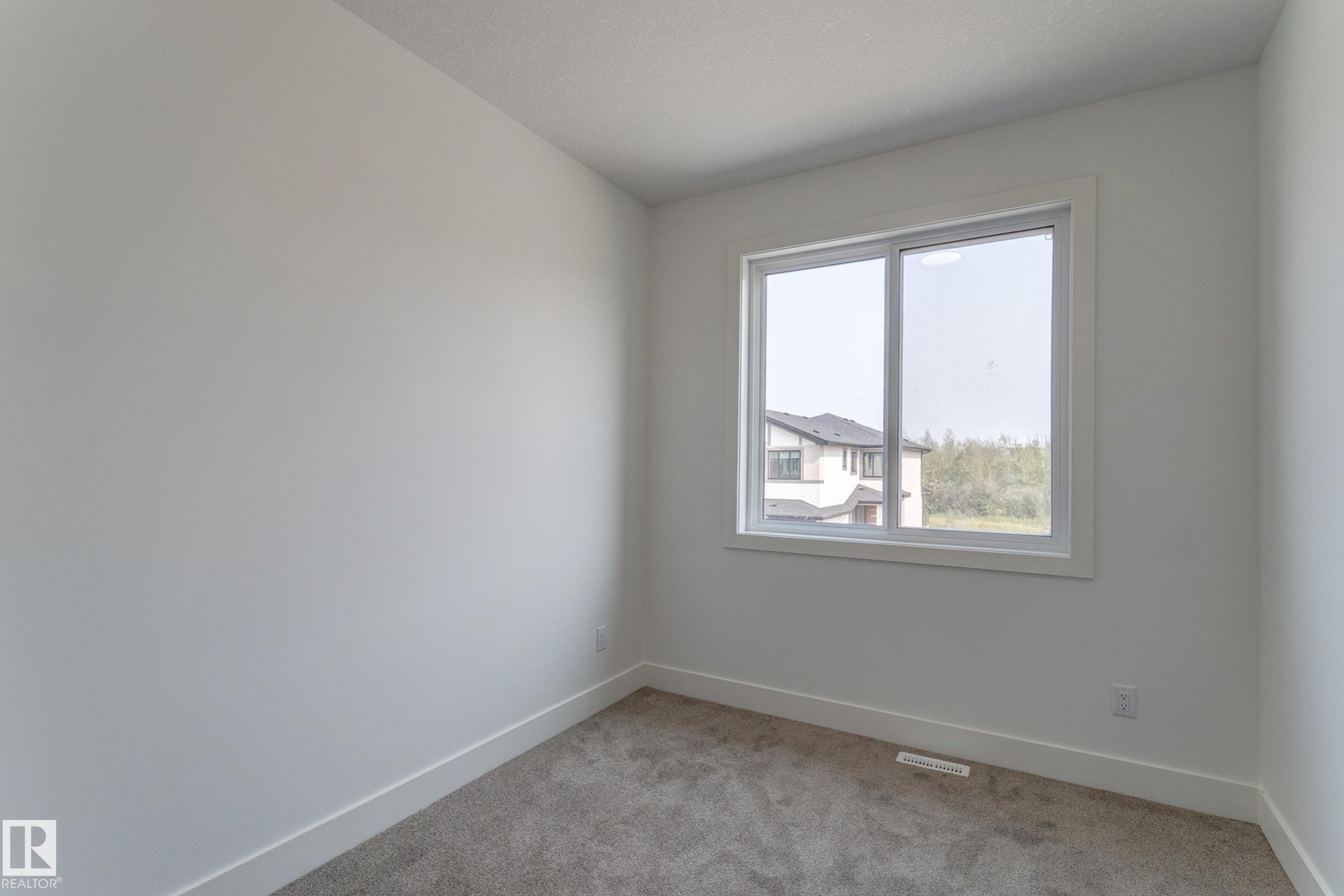 Neutral-toned room featuring a window with white trim, light gray carpeting, white walls, and white baseboards - 4723 17 Avenue Sw, Edmonton, AB - Indoor Photo Showing Other Room