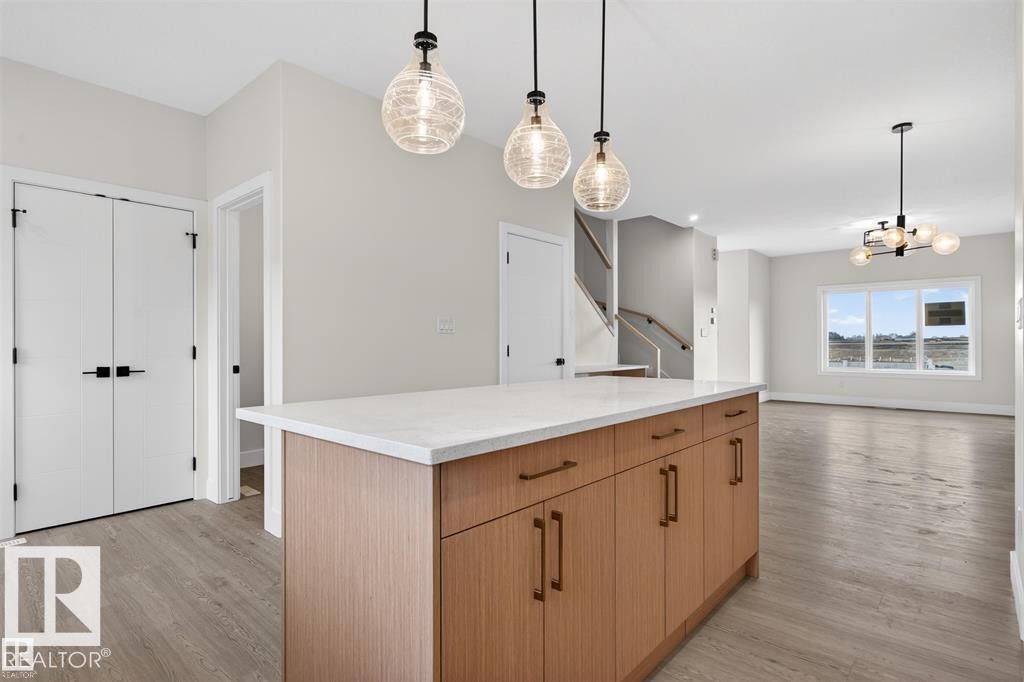 Kitchen island featuring a white countertop, wood-finish cabinetry, and bronze hardware - 43 River Birch Way, St. Albert, AB - Indoor
